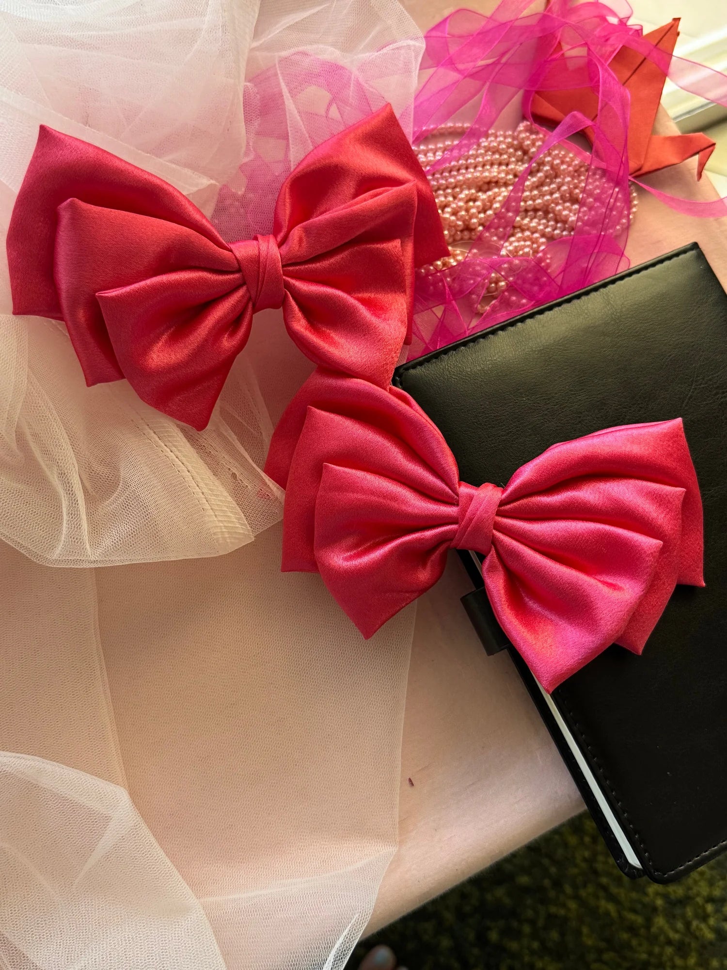 Hot pink satin hair bow by Bows and Bags India with pearl beads and tulle, handmade hair accessory styled with black clutch