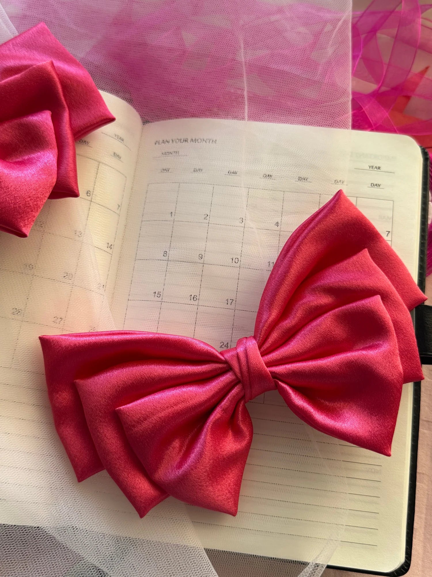 Hot pink satin hair bow by Bows and Bags India displayed on monthly planner with tulle and ribbon styling