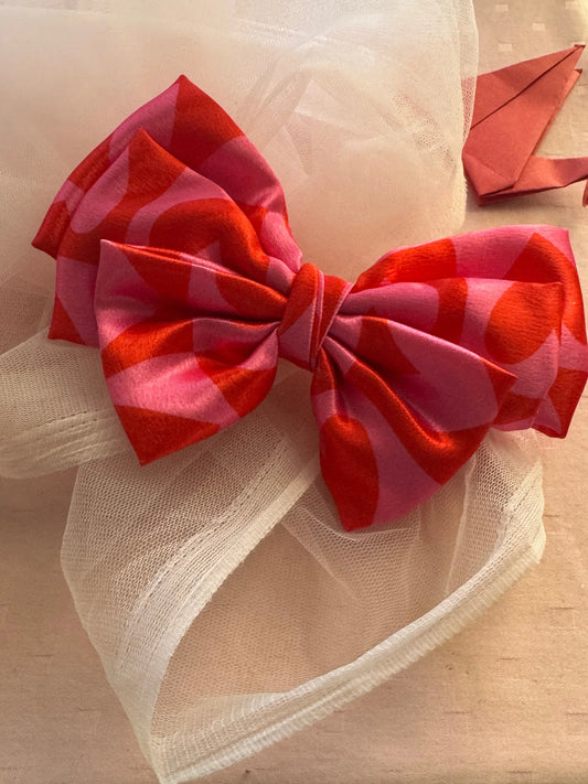 Love Stuck printed satin hair bow in pink with heart design by Bows and Bags India, displayed on cream mesh fabric