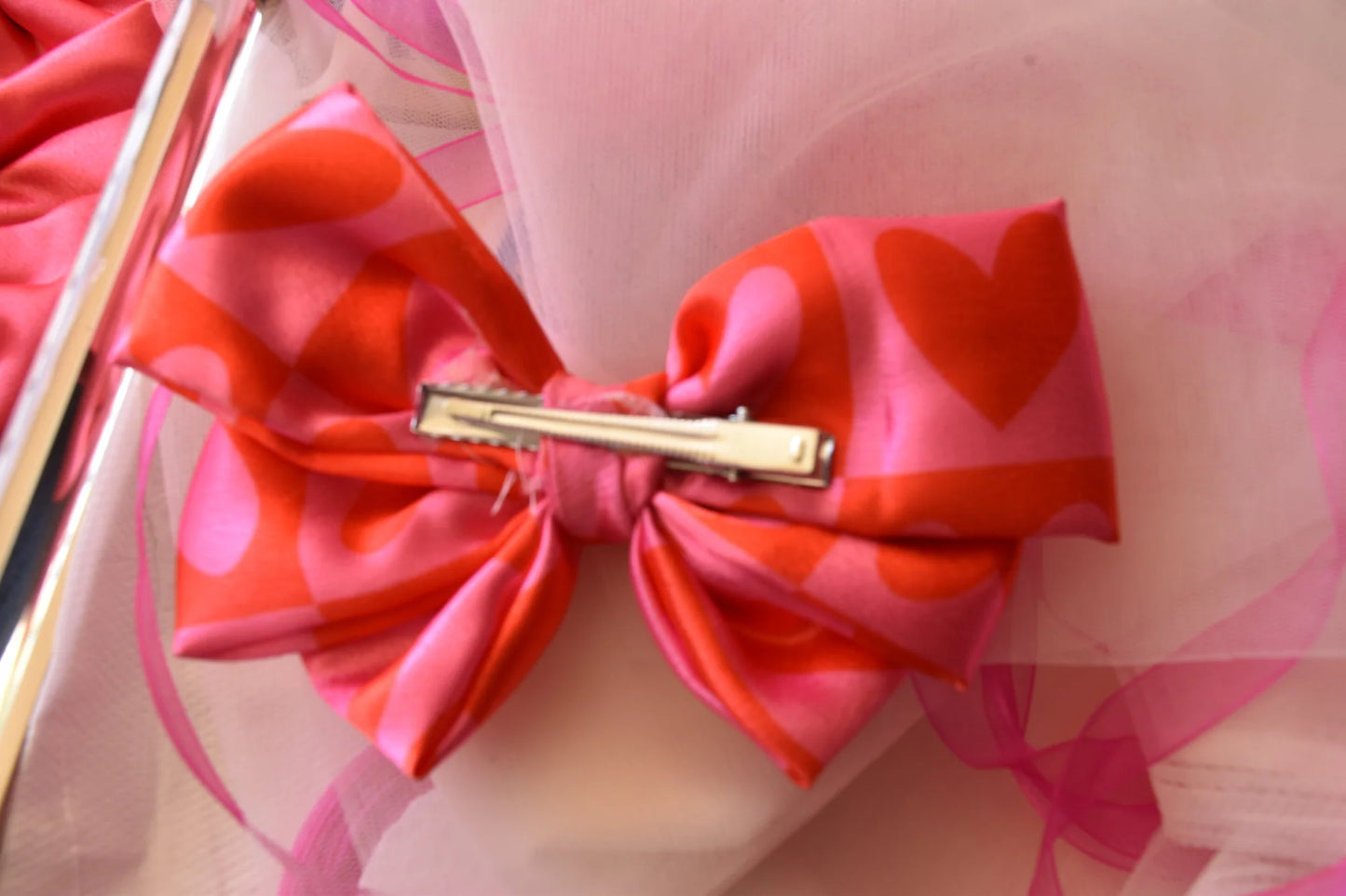 Love Stuck pink satin hair bow with heart prints and gold clip by Bows and Bags India, handmade accessory detail shot