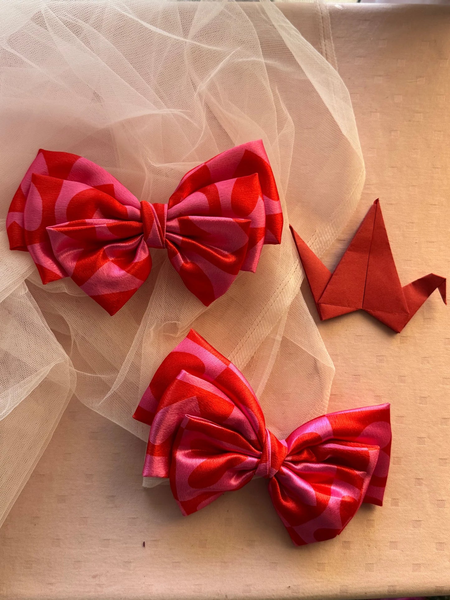 Love Stuck printed satin hair bow in pink with heart details by Bows and Bags India, displayed with origami crane and tulle