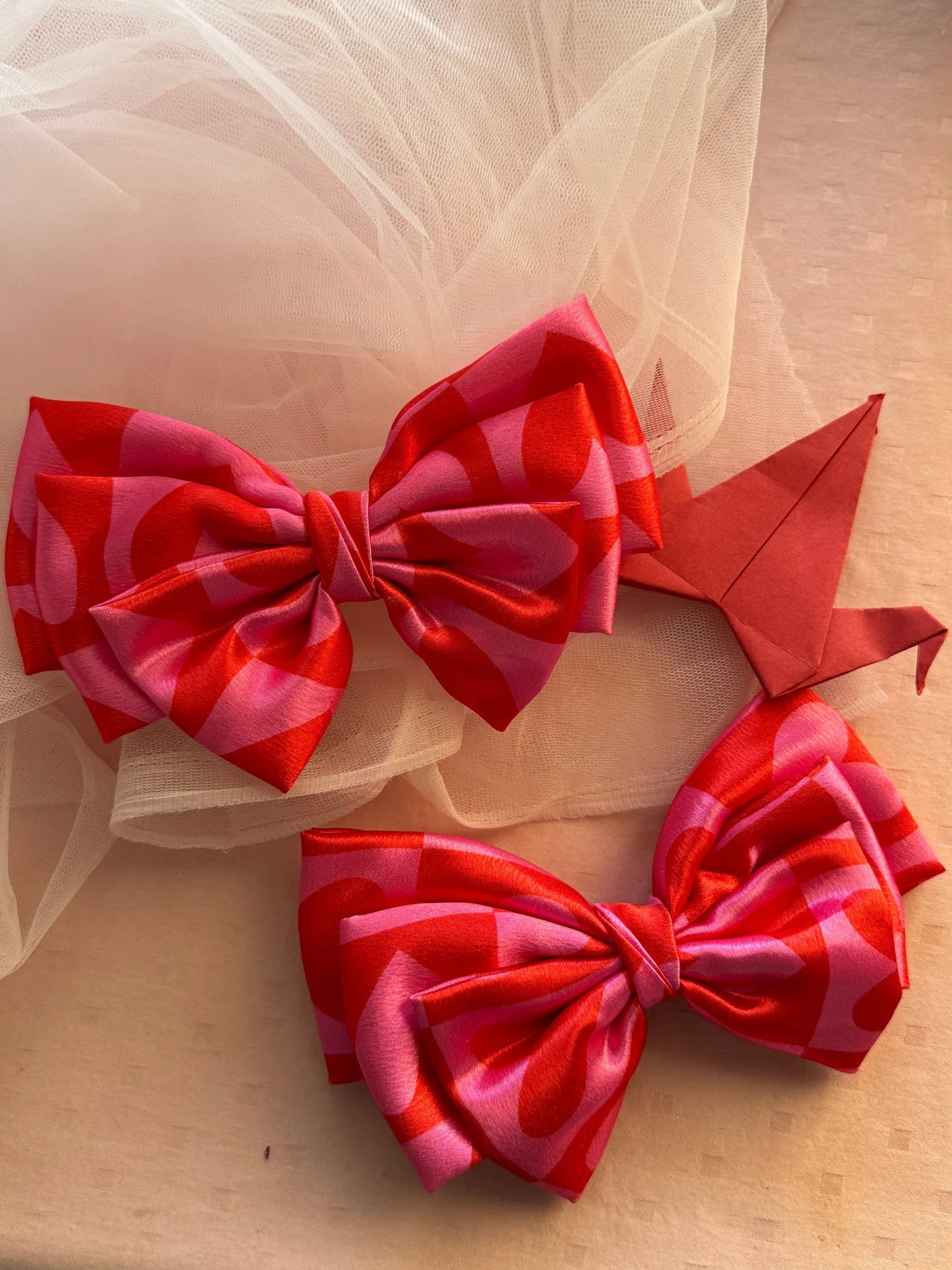 Pink printed satin hair bow with heart design by Bows and Bags India, handmade accessory displayed with tulle fabric
