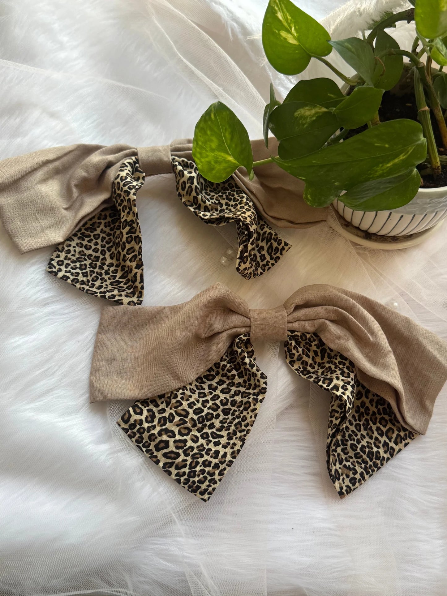 Beige and leopard print Madonna hair bow with satin finish by Bows and Bags India, displayed on white fabric with green