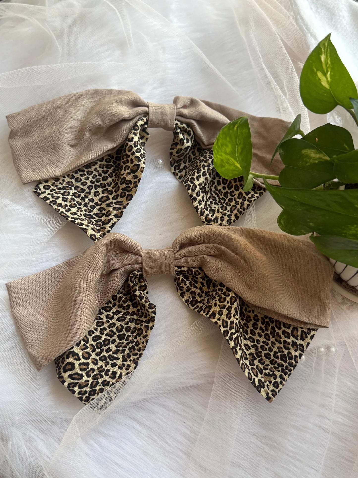 Beige and leopard print Madonna hair bows from Bows and Bags India displayed flat lay with green leaves
