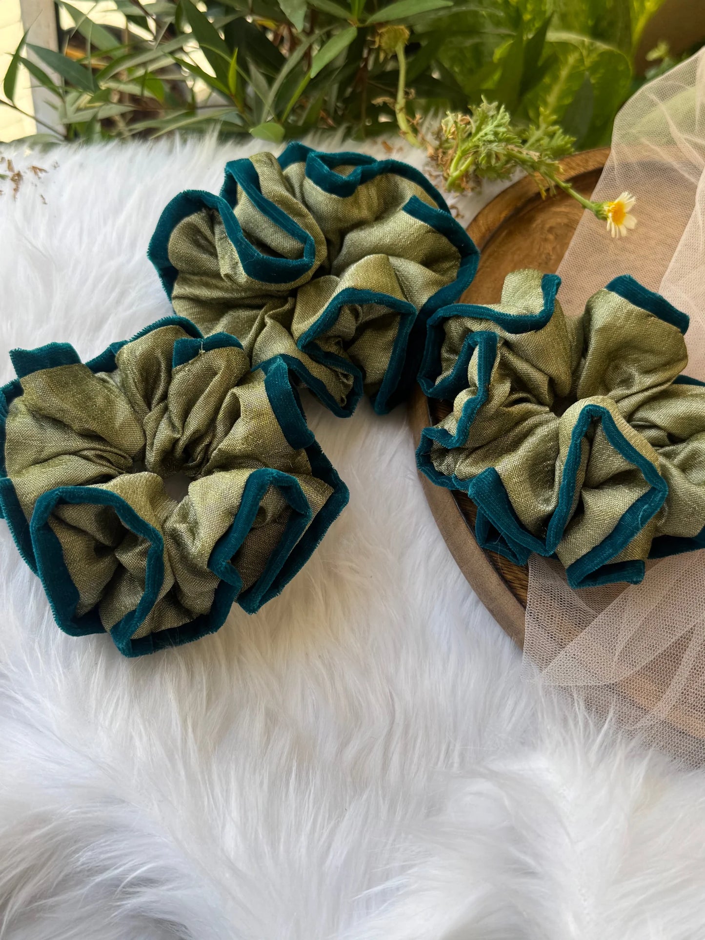Mint green silk and velvet scrunchies by Bows and Bags India arranged on white fur, showing handmade texture and dark green