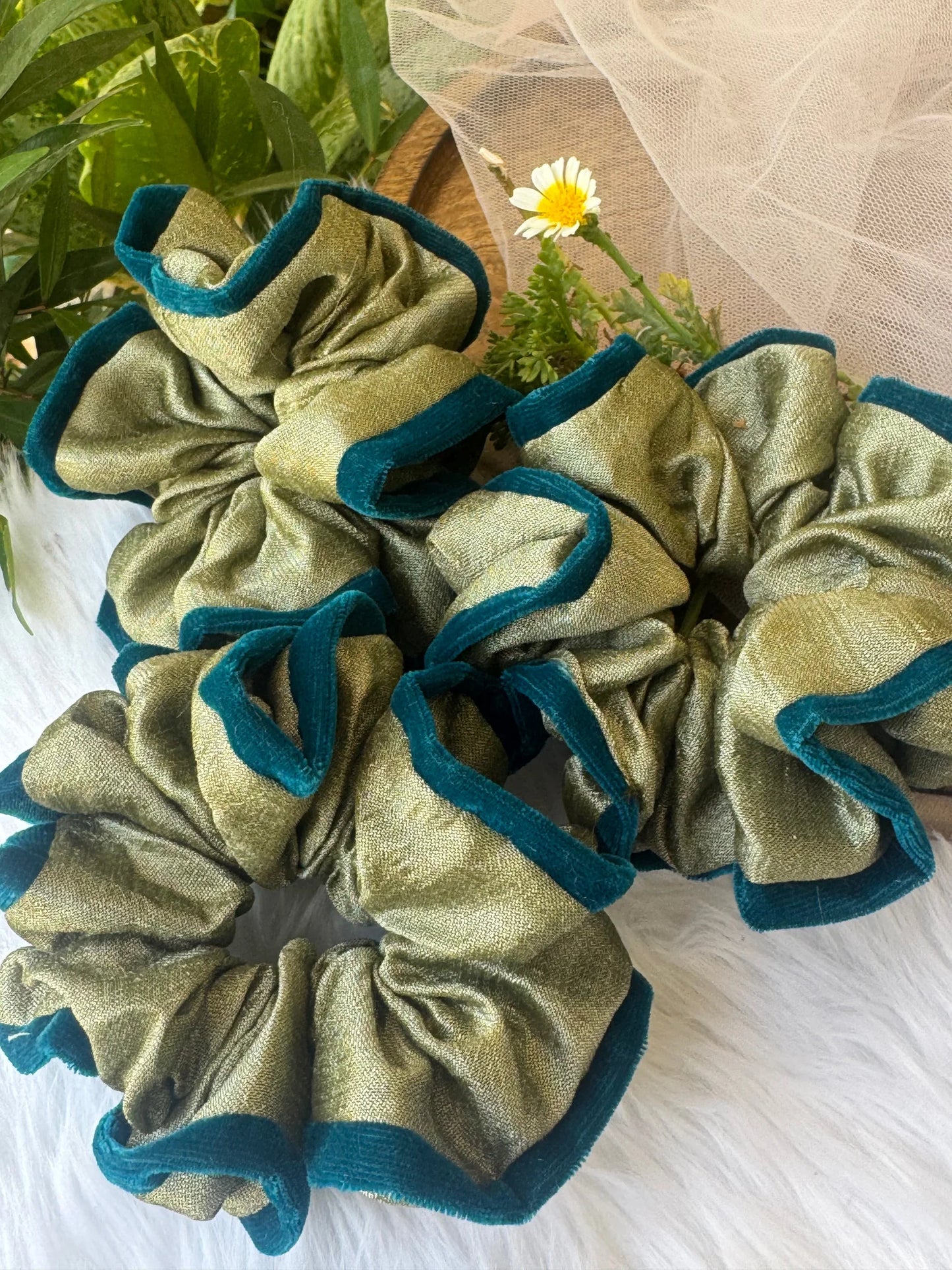 Mint green silk scrunchie with dark teal velvet trim displayed on white fabric with daisy flower, Bows and Bags India