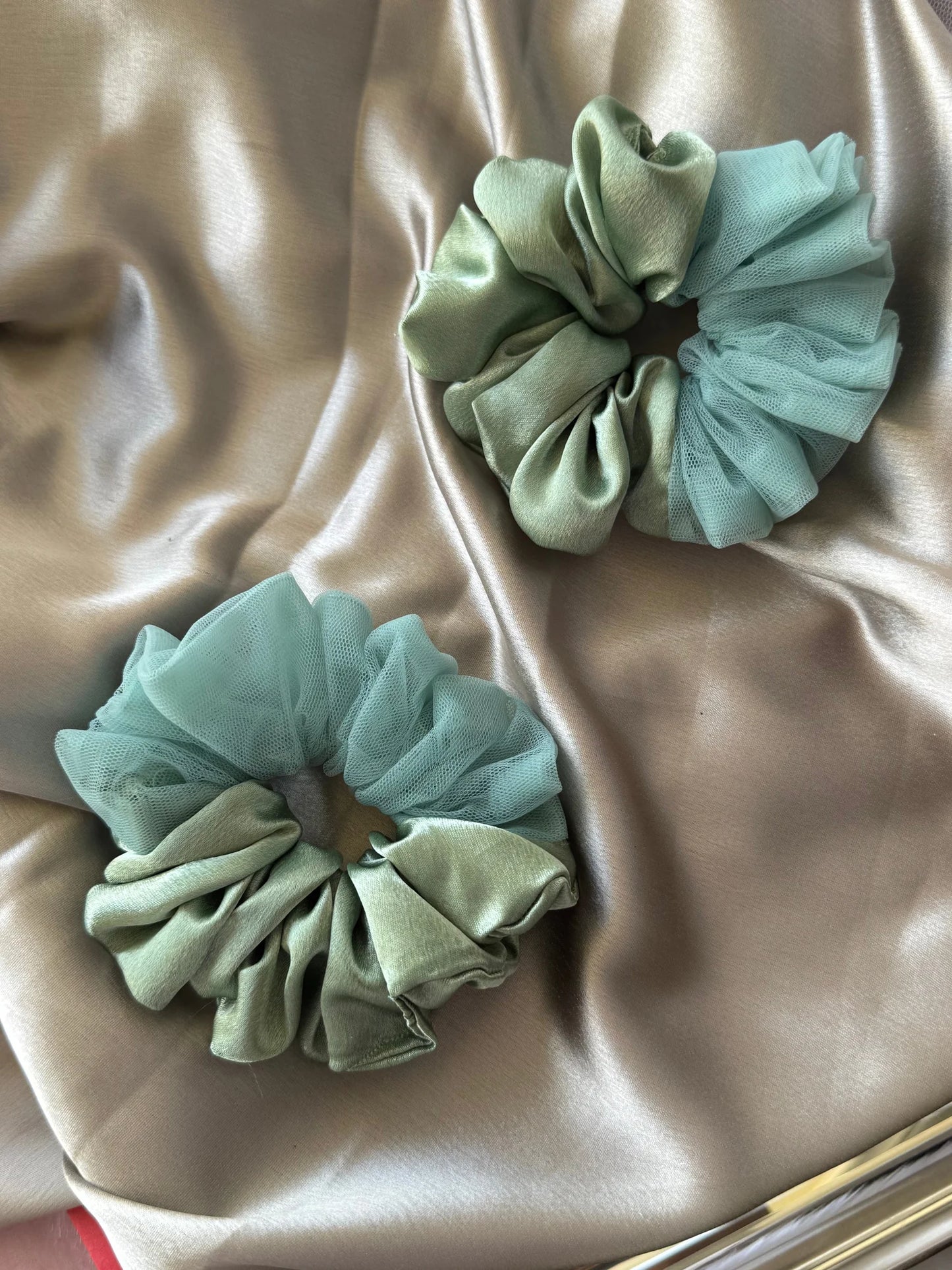 Mint green metallic satin and net scrunchies by Bows and Bags India displayed on champagne silk fabric showing handmade hair