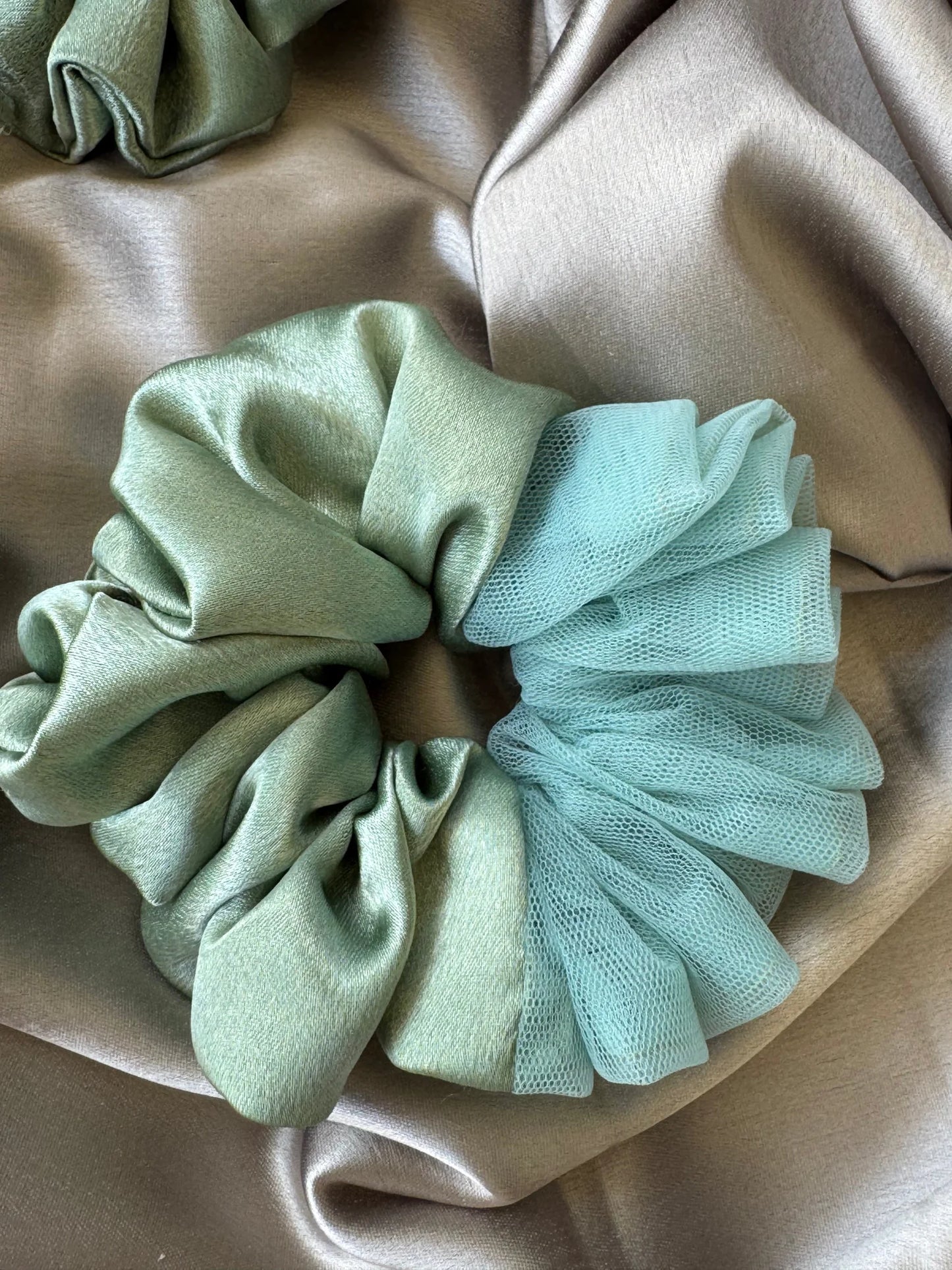 Metallic mint green satin and delicate net scrunchies displayed on neutral fabrics, handmade hair accessories by Bows and