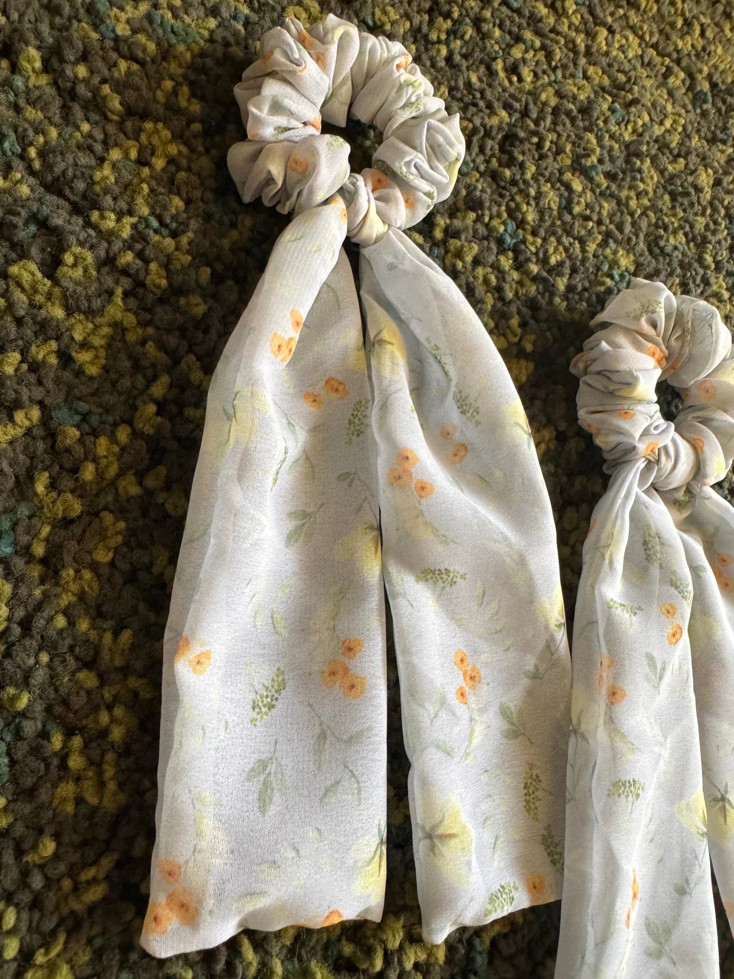 Floral green georgette tail scrunchie with flowing tails displayed flat on textured background by Bows and Bags India