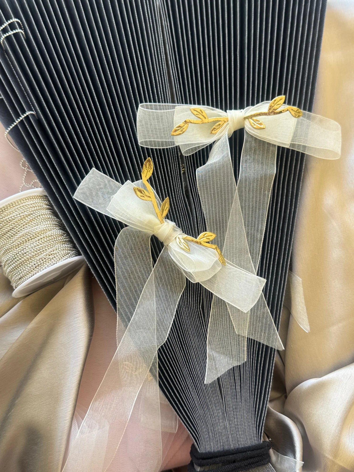 White transparent bow hair clip with gold leaf details on black ribbed fabric, styled by Bows and Bags India