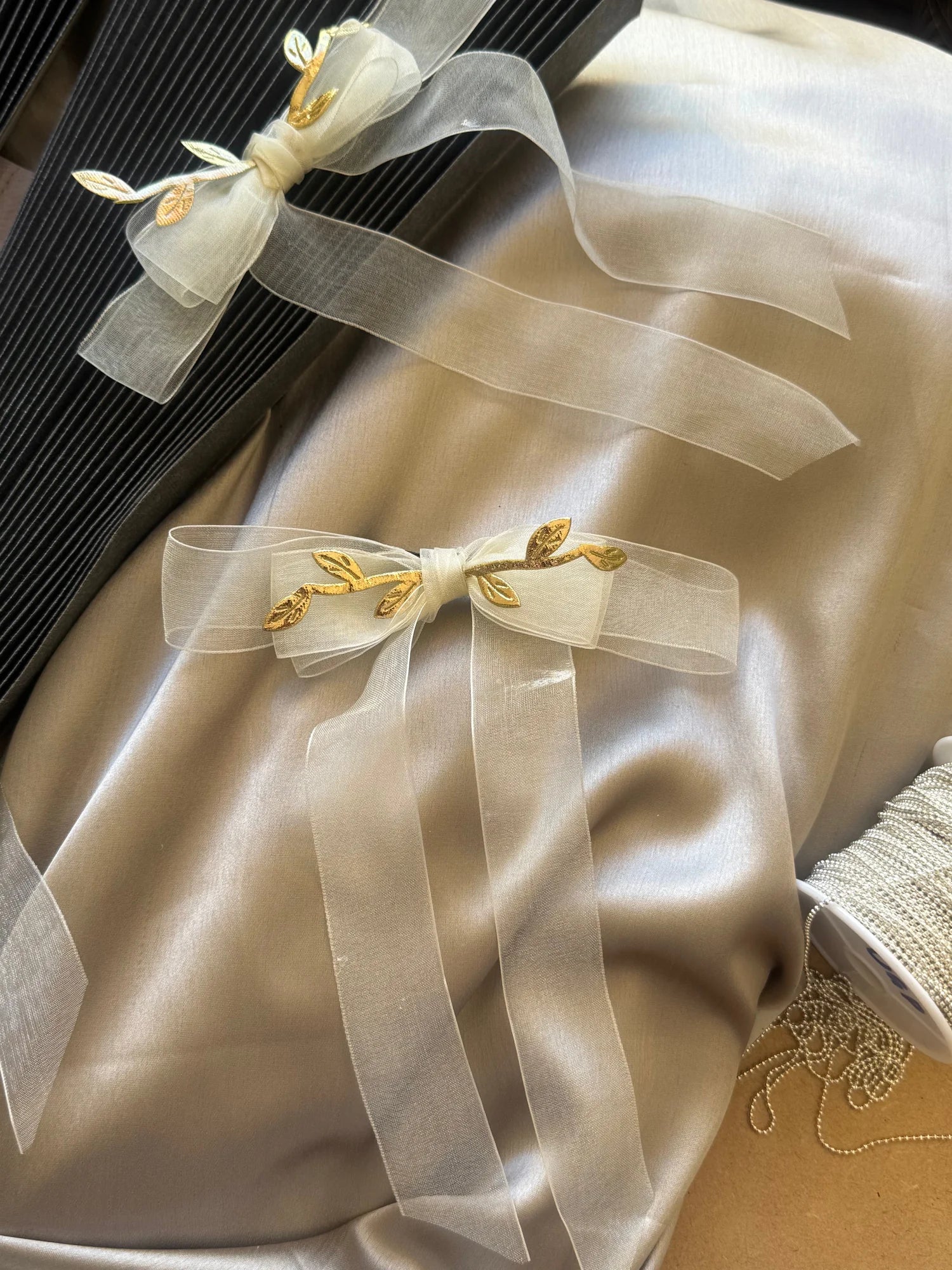 White organza hair bow with gold leaf details on cream silk fabric by Bows and Bags India