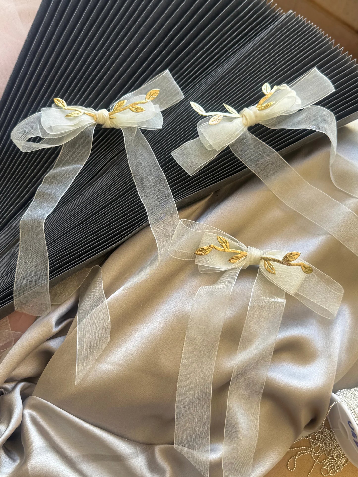 White transparent hair bow with gold leaf detailing on cream fabric, Bows and Bags India handmade hair clip accessory display