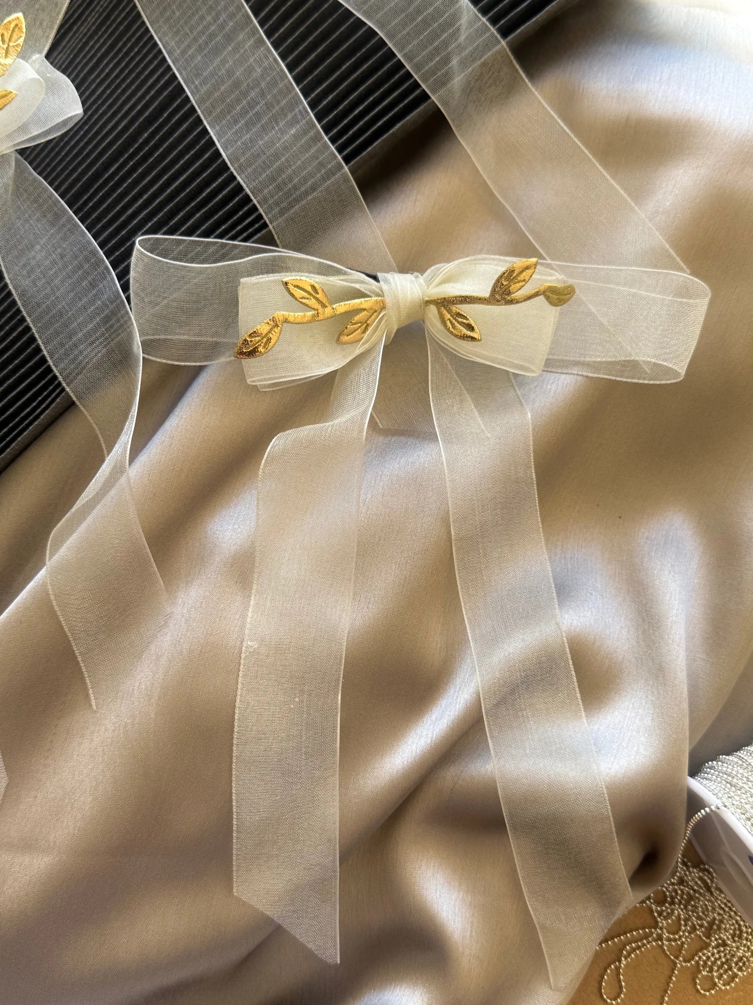 White transparent organza bow with gold leaf embellishments, handmade hair clip by Bows and Bags India, close-up detail shot