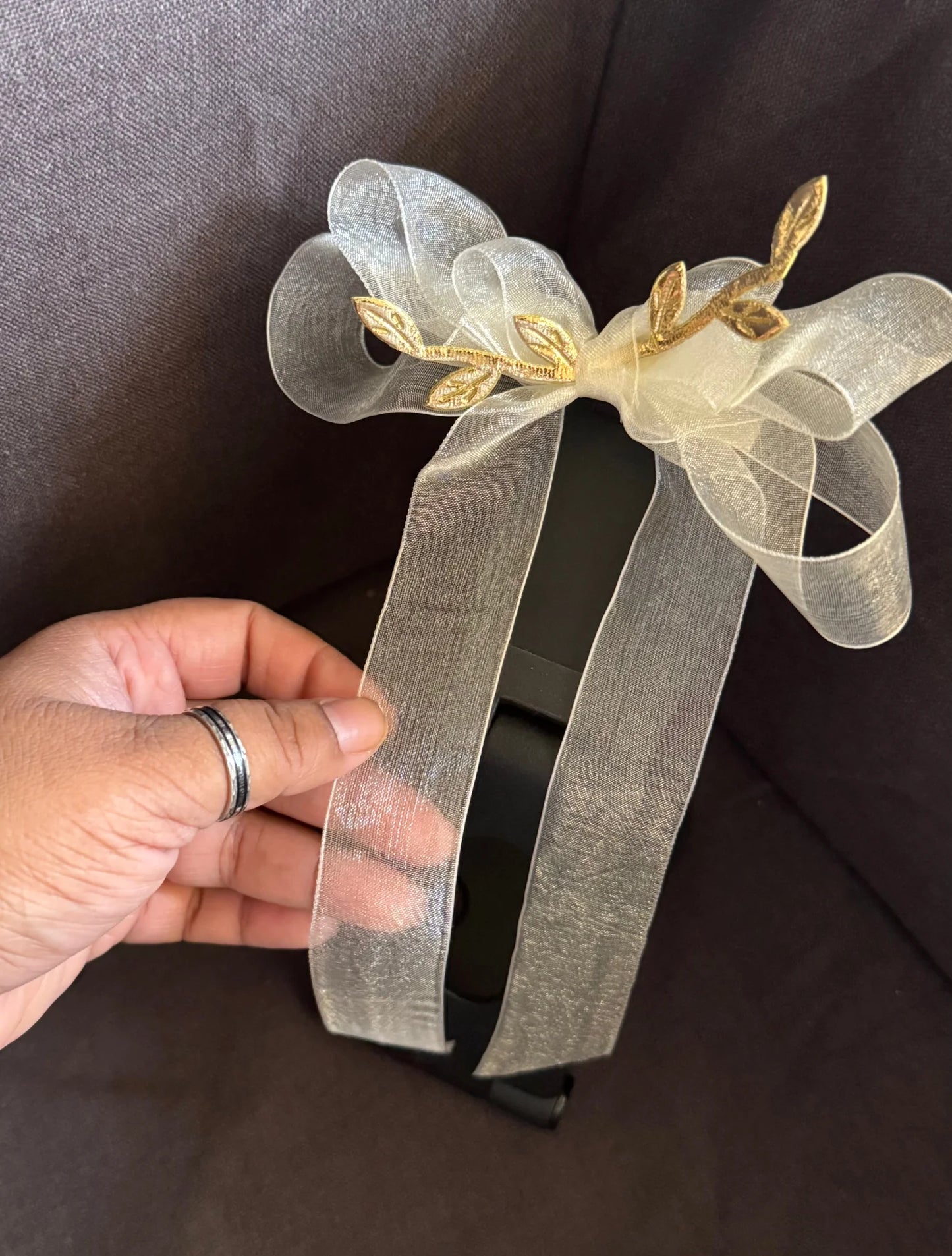 White transparent bow hair clip with gold leaf accents held in hand, handmade accessory by Bows and Bags India