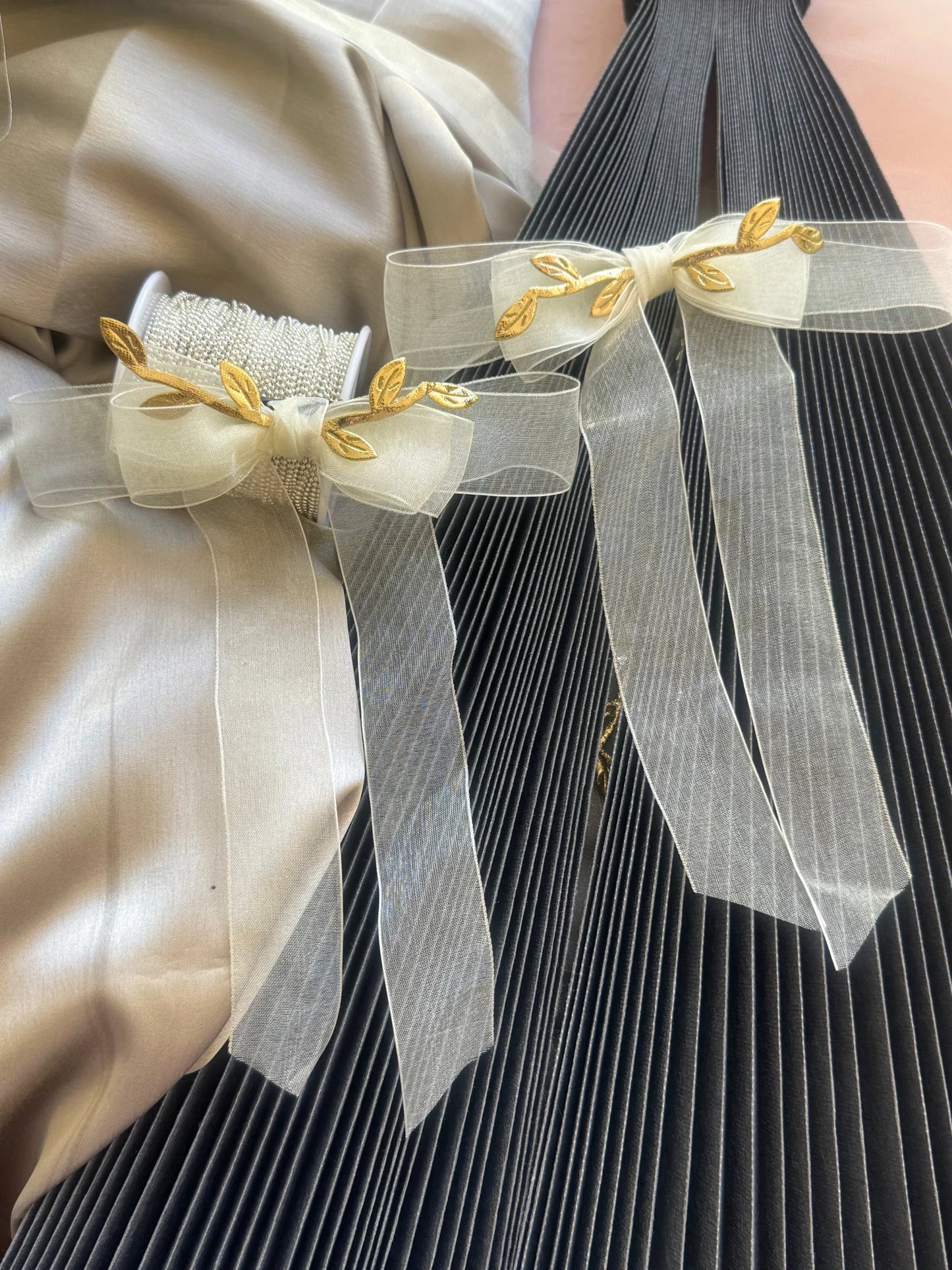 O So Roman hair clip with white sheer bow and gold leaf details displayed on model wearing pleated dress by Bows and Bags