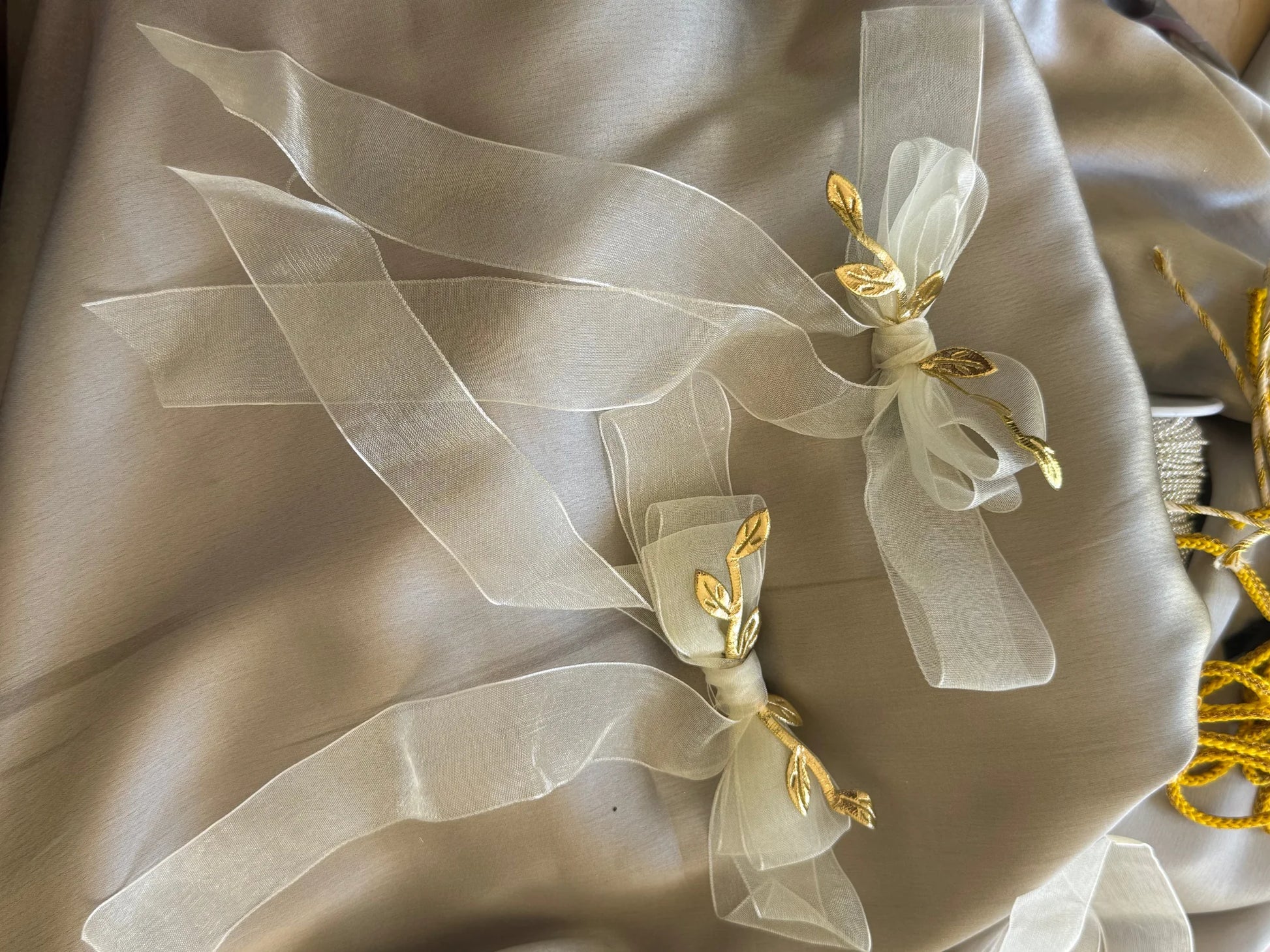 White transparent bow hair clip with gold leaf detailing on cream silk fabric by Bows and Bags India