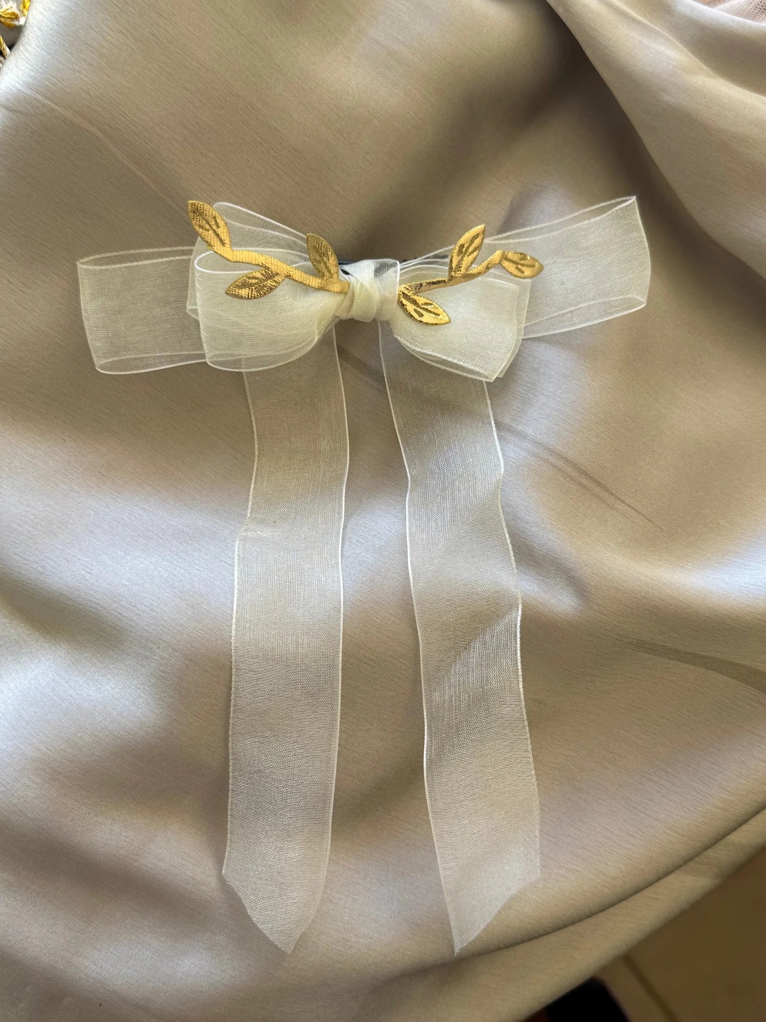 Ivory sheer bow hair clip with gold leaf accents on cream fabric, Bows and Bags India handmade accessory detail shot