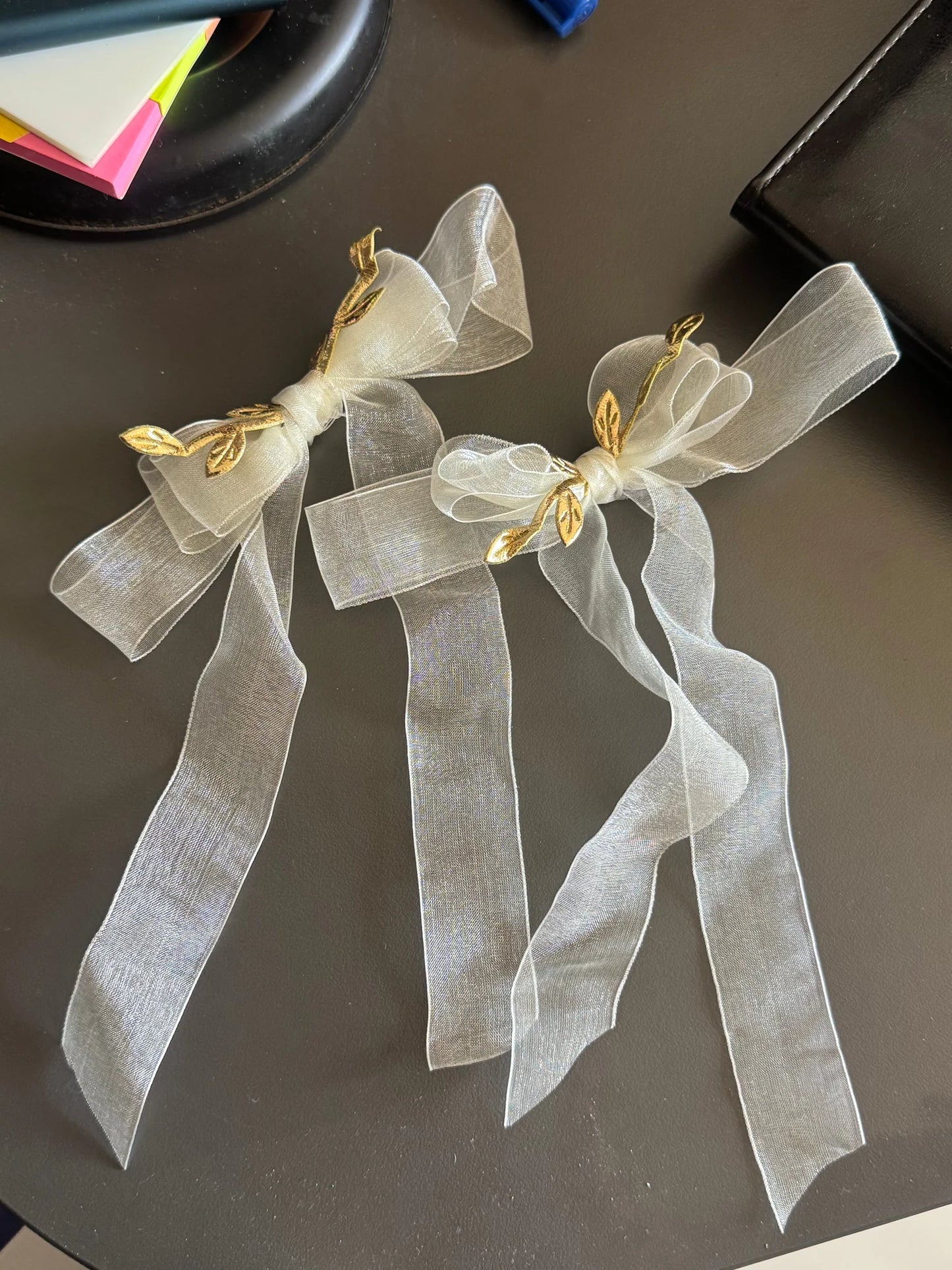 White transparent organza hair bow with gold metal accents by Bows and Bags India, handmade hair clip displayed on dark