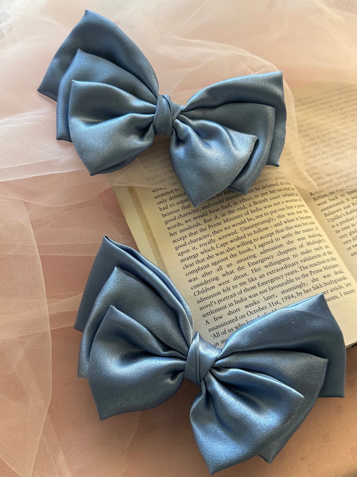 Metallic ice blue satin hair bows by Bows and Bags India displayed on open book with tulle, handmade hair accessories detail