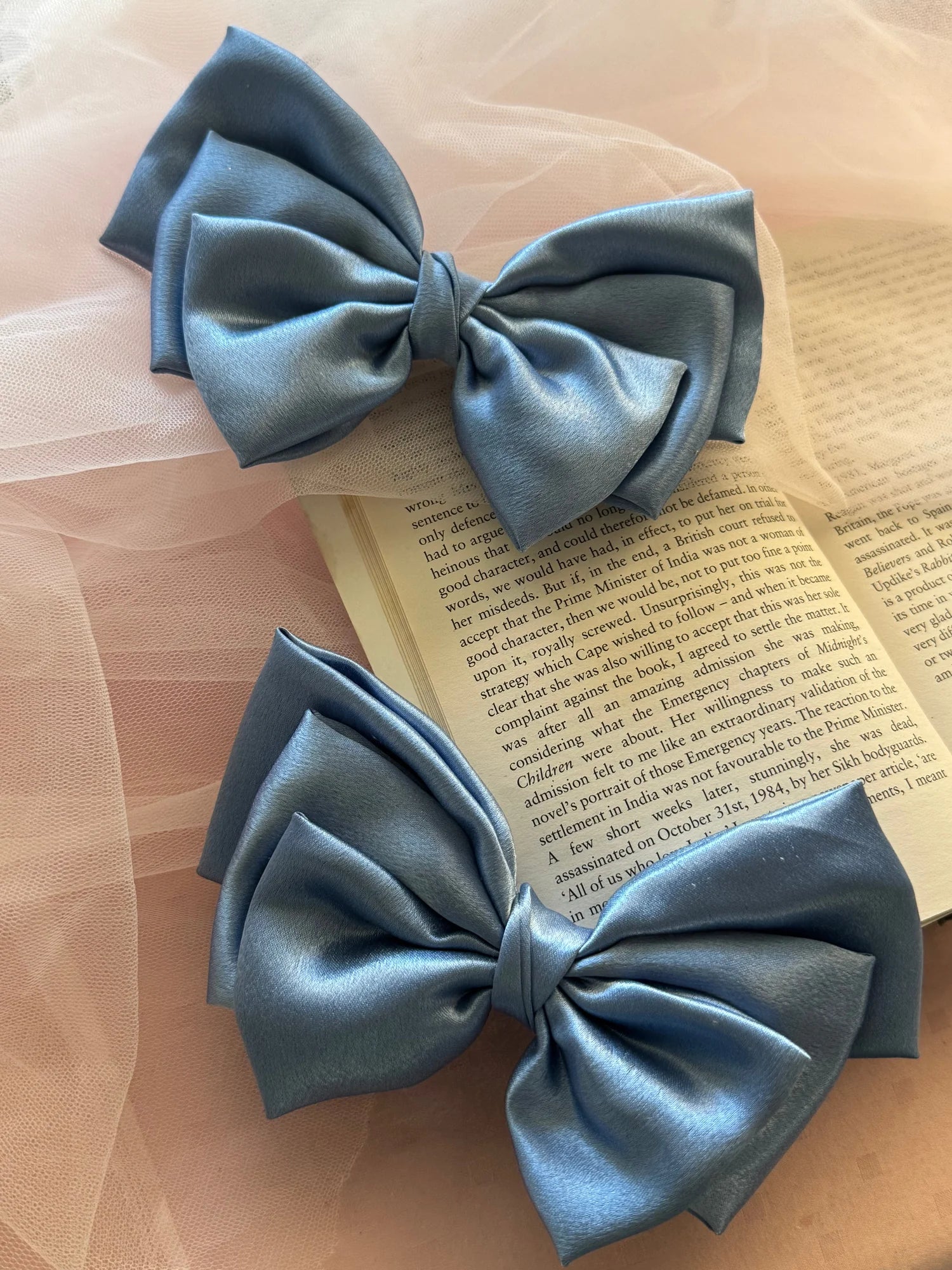 Metallic ice blue satin hair bows by Bows and Bags India displayed on open book with tulle, handmade hair accessories detail