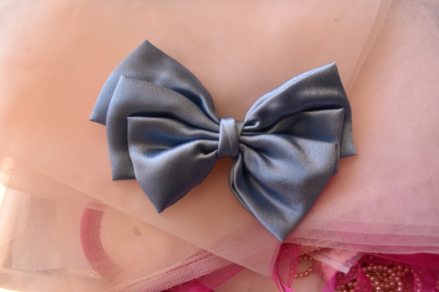 Metallic ice blue satin hair bow by Bows and Bags India displayed on pink tulle, showing elegant bow knot detail and