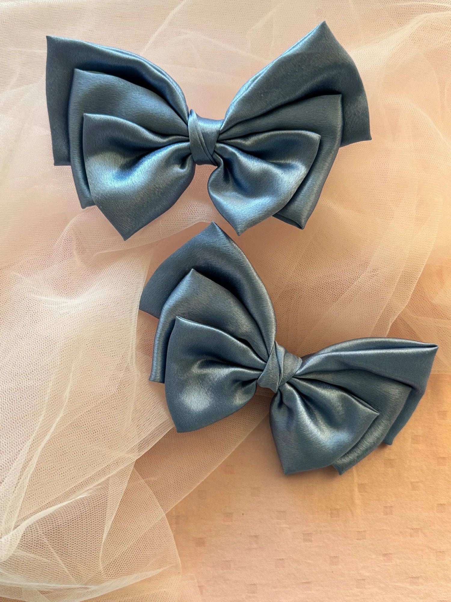 Metallic ice blue satin hair bows by Bows and Bags India displayed on tulle, showing handmade texture and elegant draping