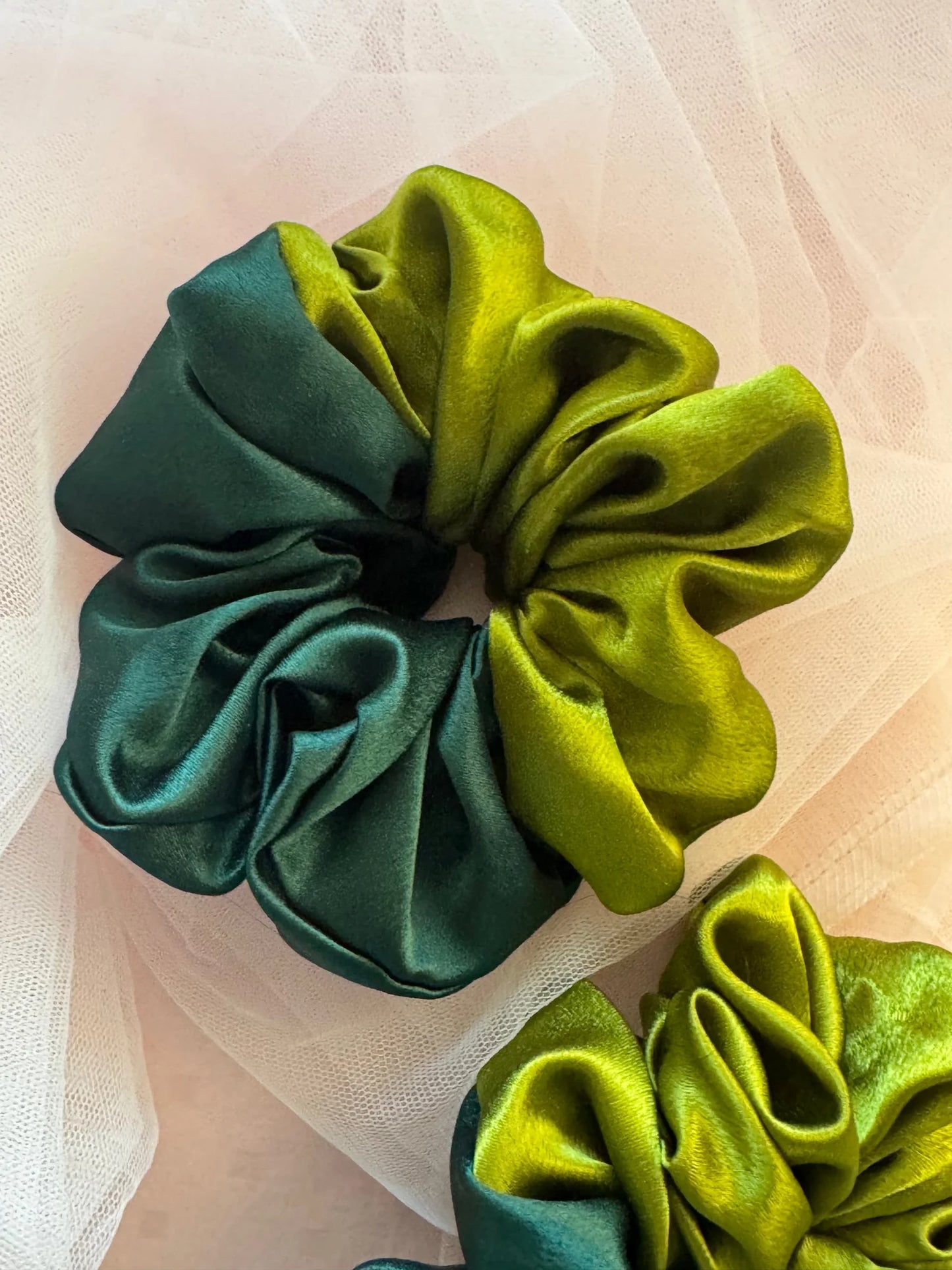 Dual-color olive and dark green satin scrunchies by Bows and Bags India displayed on soft fabric, showcasing handmade hair