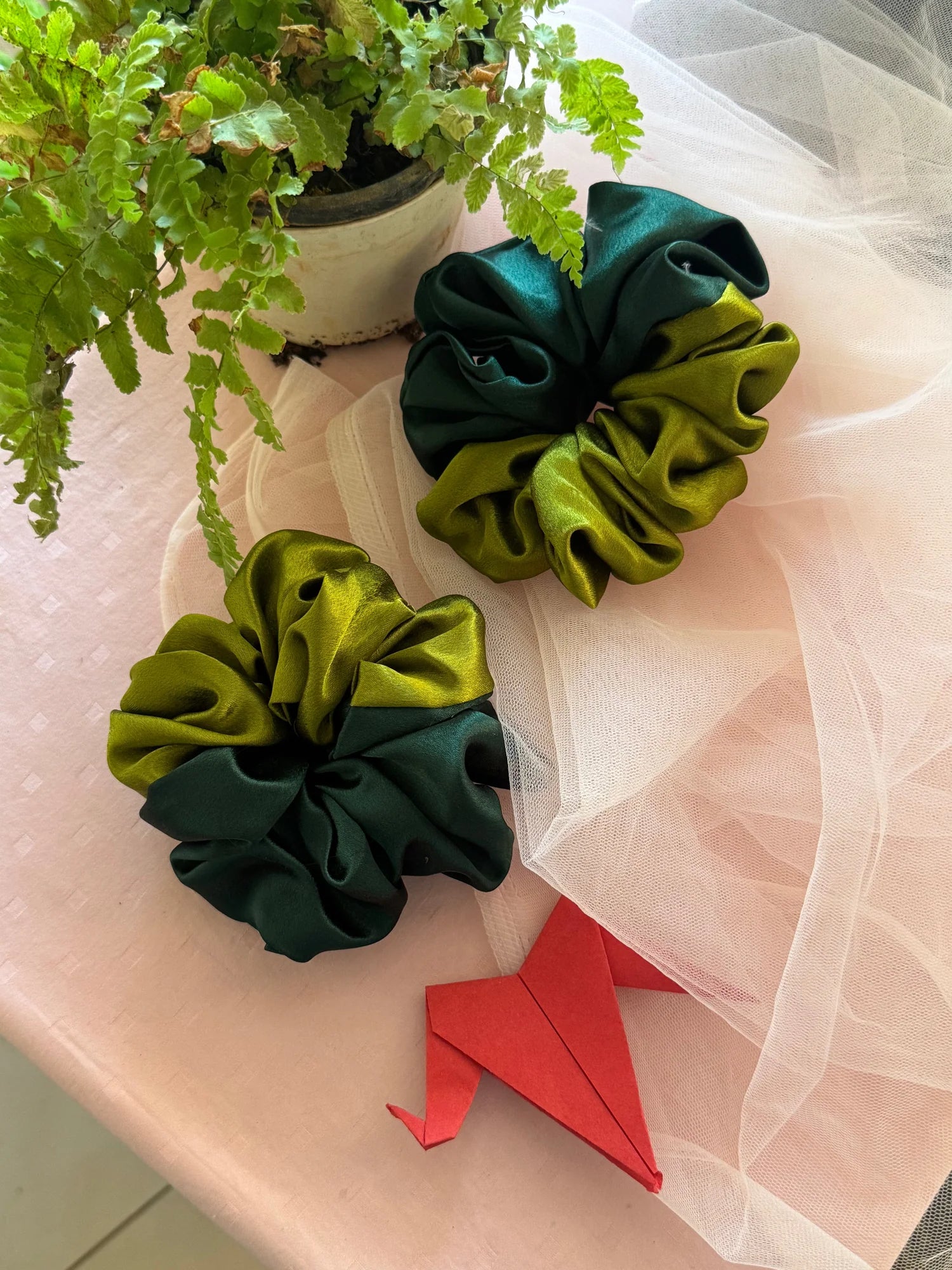 Olive and dark green satin scrunchies by Bows and Bags India displayed on sheer fabric with decorative elements, showing
