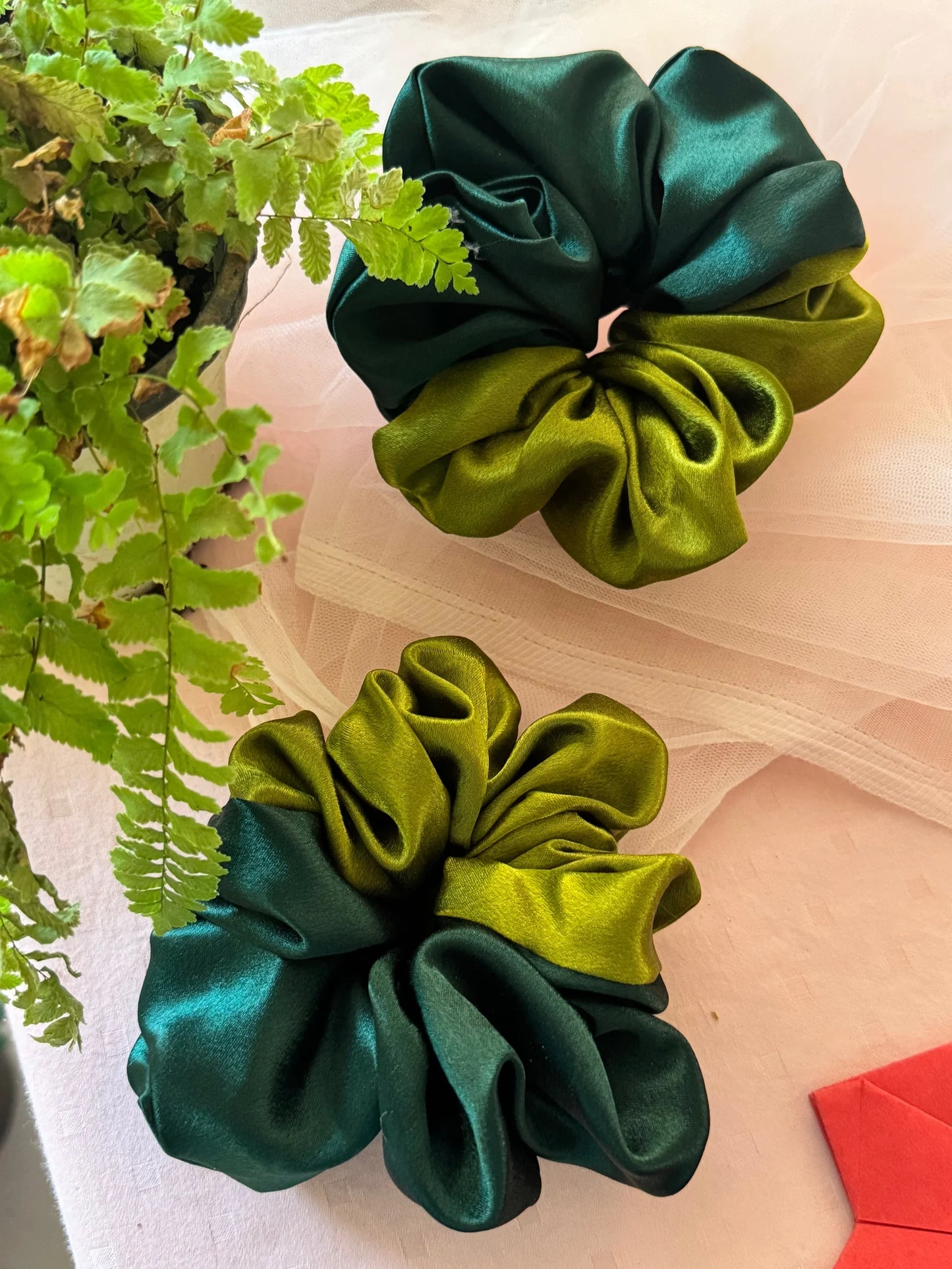 Olive Garden dual-colour satin scrunchies in olive and dark green displayed flat with fresh herbs, handmade hair accessories