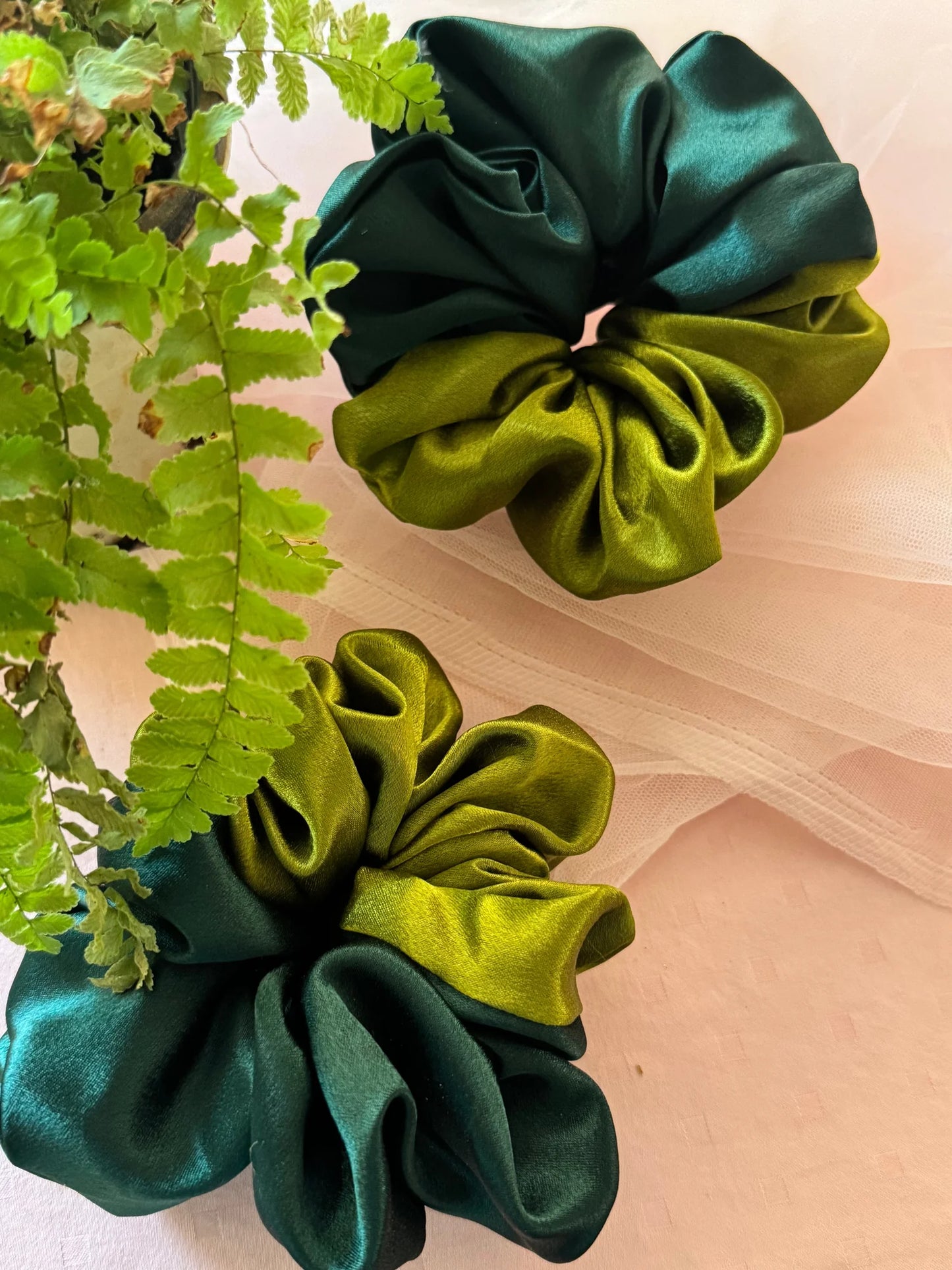 Olive Garden satin scrunchies in olive and dark green, handmade by Bows and Bags India, displayed with fresh greenery on