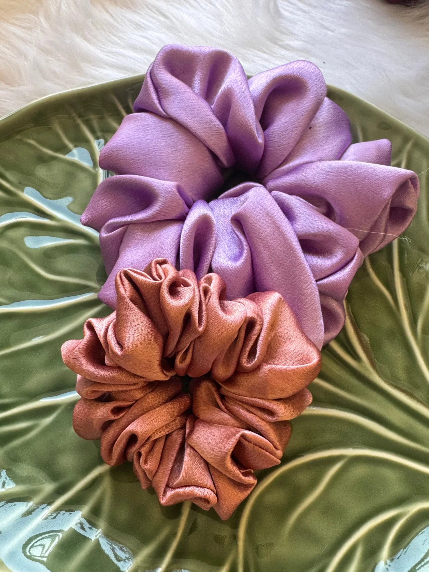 Lavender and peach satin scrunchies combo displayed on green fabric, showing soft fluffy texture by Bows and Bags India