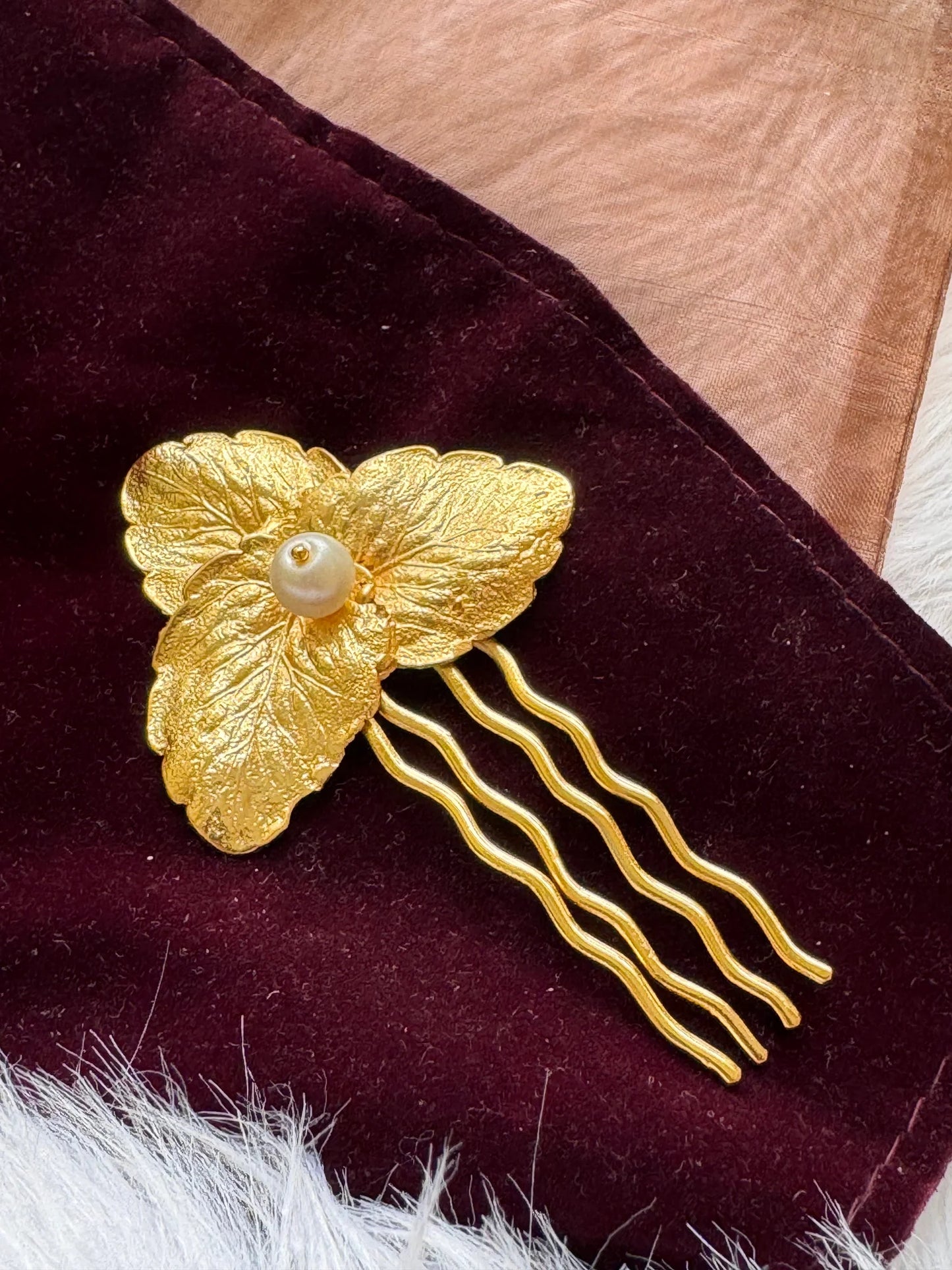 Pearl Golden Leaf hair pin by Bows and Bags India on maroon velvet, showing textured gold leaves with lustrous pearl center