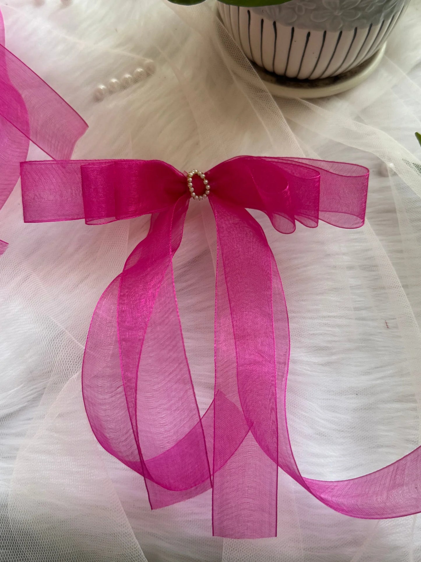 Pink organza hair bow with pearl center detail by Bows and Bags India, handmade accessory displayed on white tulle fabric
