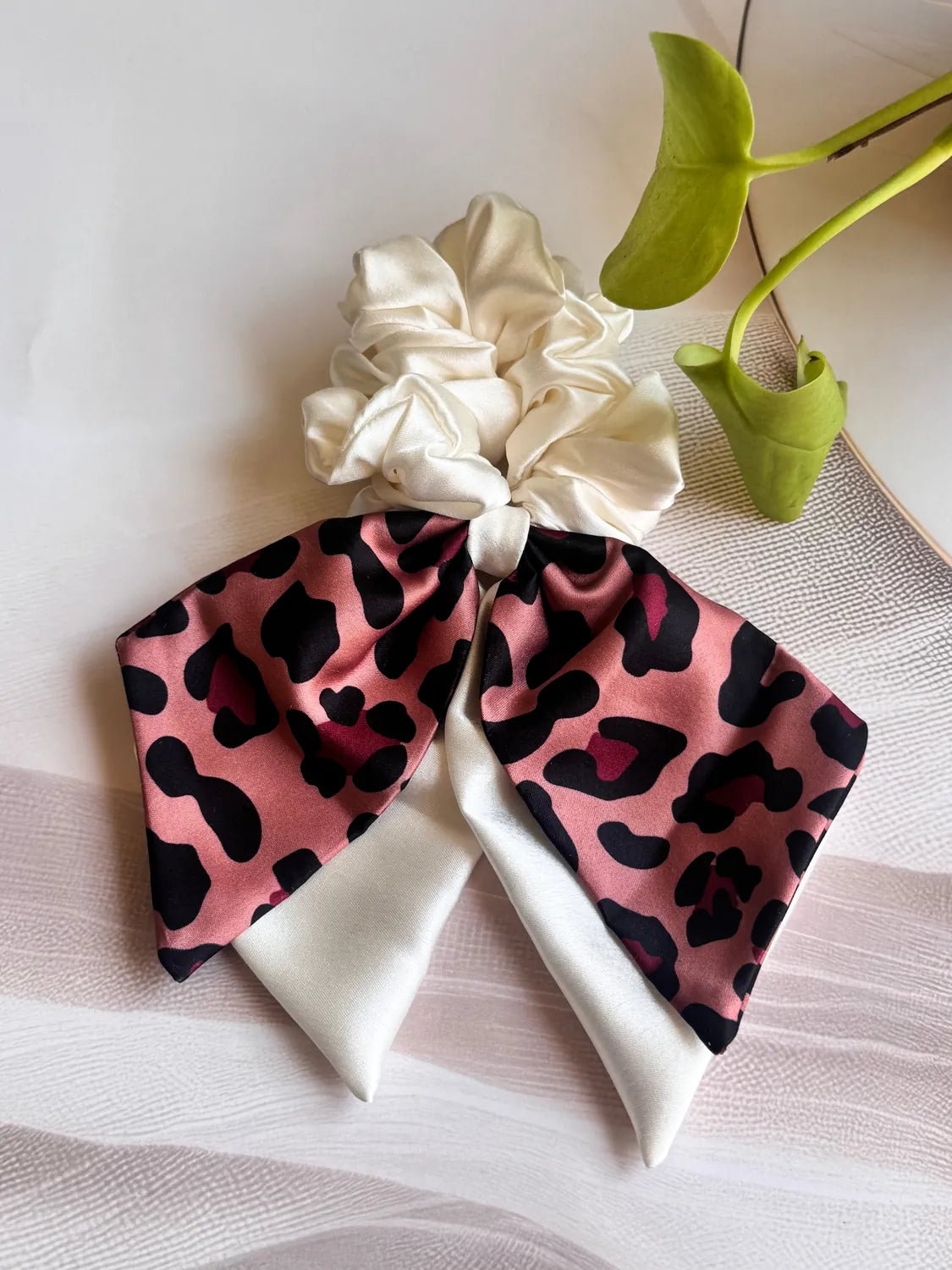 Dusty rose leopard print satin bow scrunchie with dual long tails by Bows and Bags India, handmade hair accessory displayed