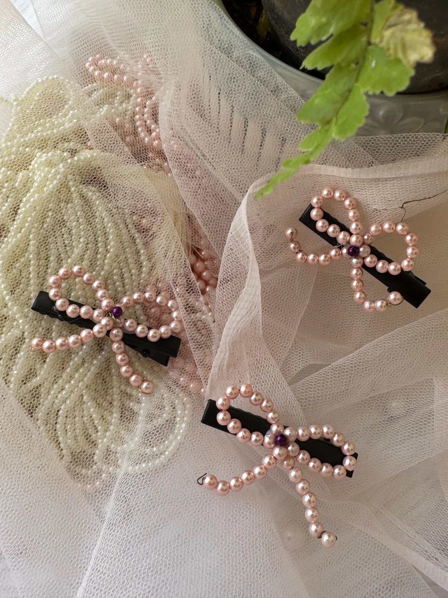 Pink pearl bow hair clips with black metal clips displayed on tulle fabric by Bows and Bags India handmade accessories