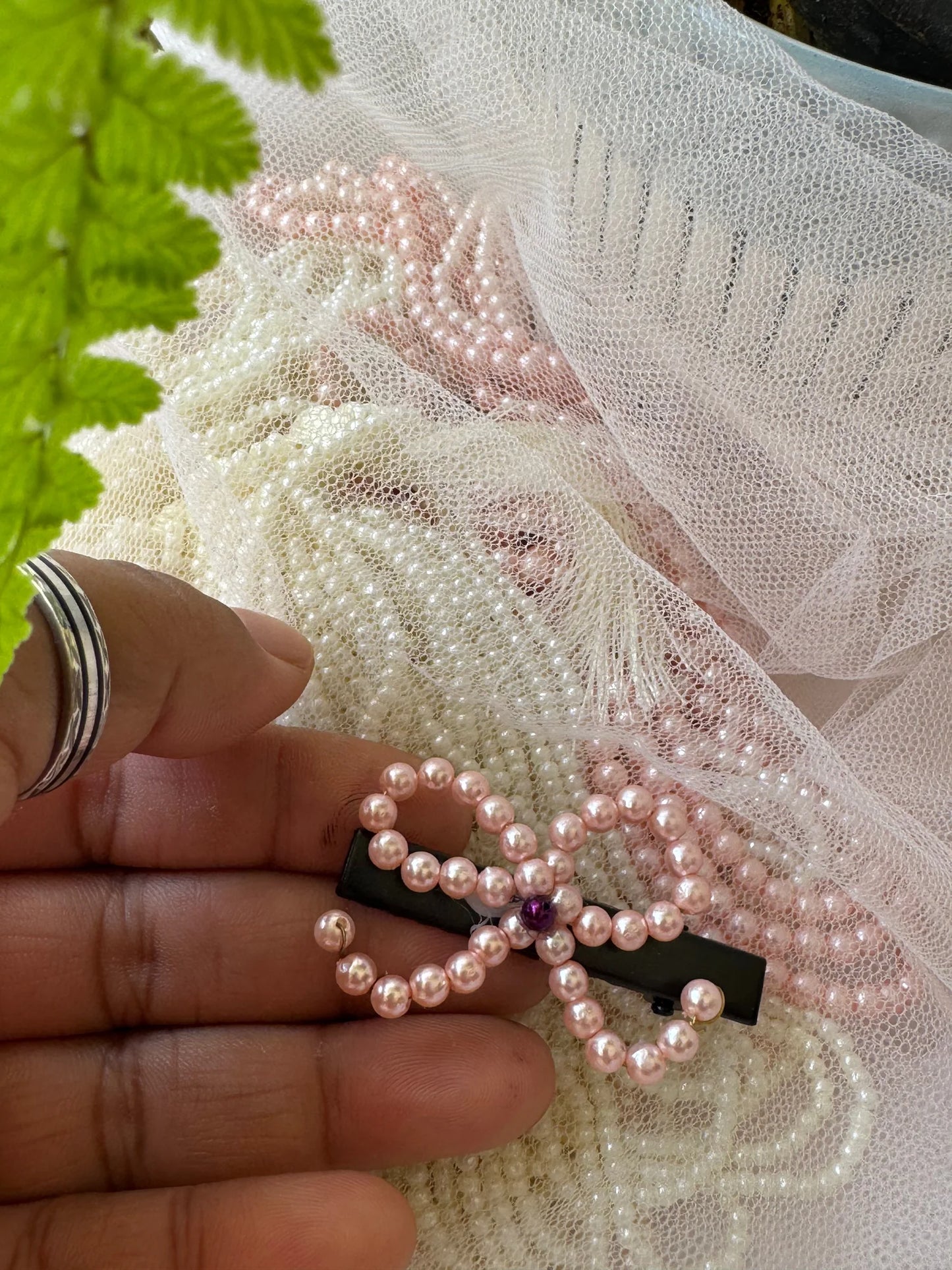 Close-up of pink pearl beaded hair clip held in hand, showing delicate pearl strings and handmade detail by Bows and Bags