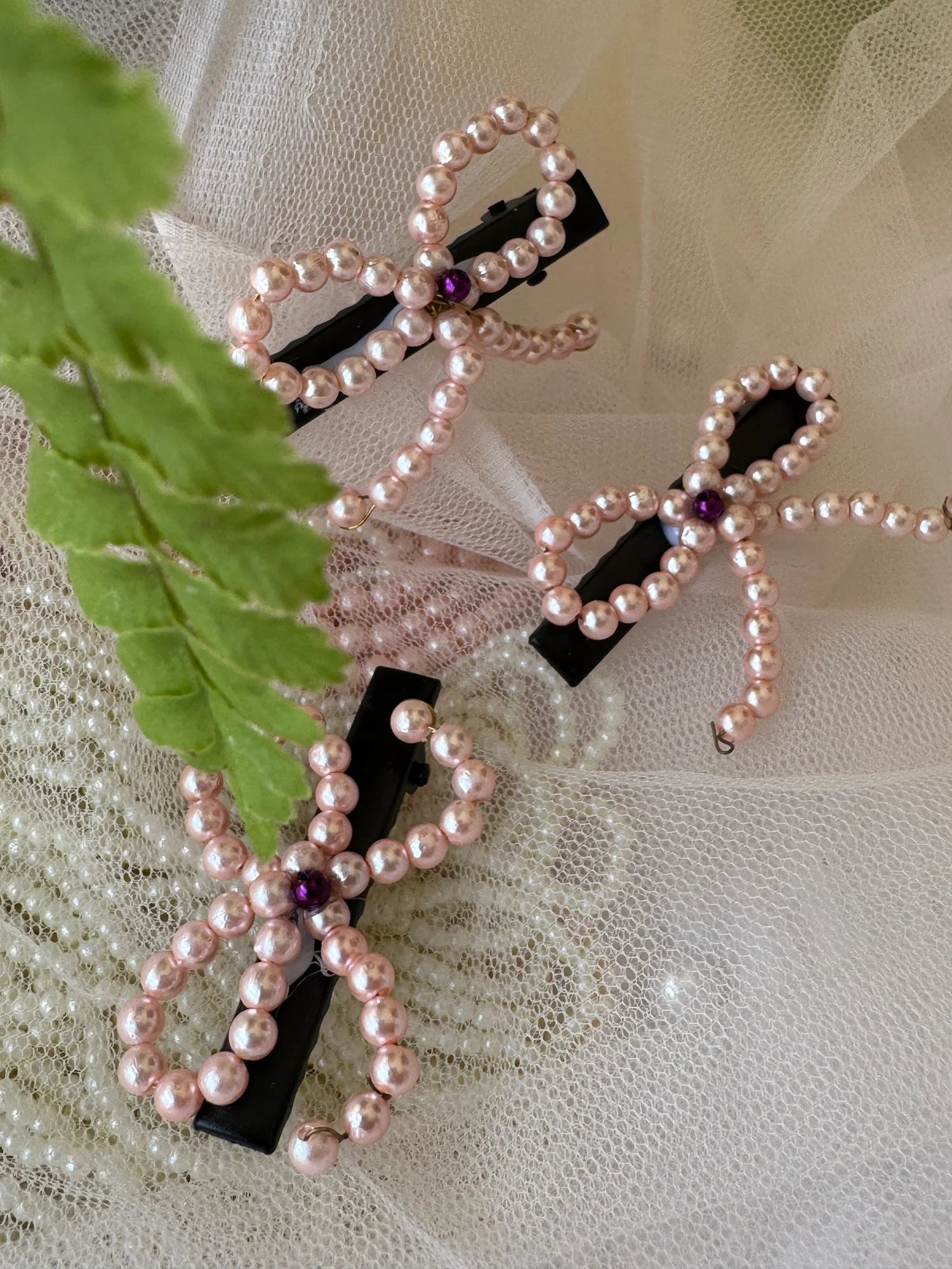 Pink pearl bow hair clips with black base and purple accents by Bows and Bags India, handmade pearl stringed accessories