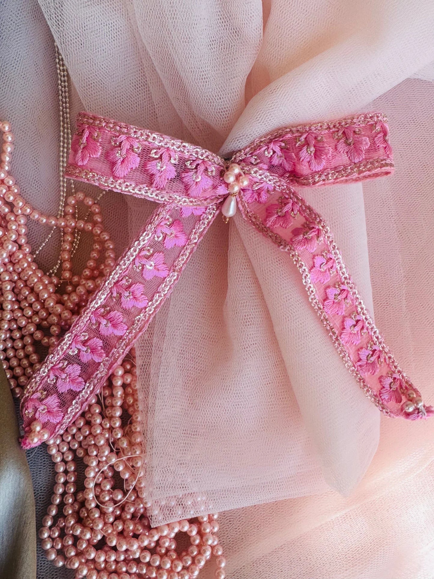 Pink pearl flower hair clip with intricate floral embroidery and beaded details on soft tulle backdrop by Bows and Bags India