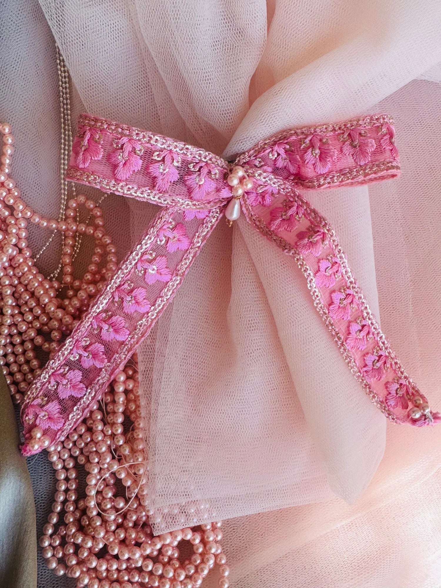 Pink pearl flower hair clip with intricate floral embroidery and beaded details on soft tulle backdrop by Bows and Bags India