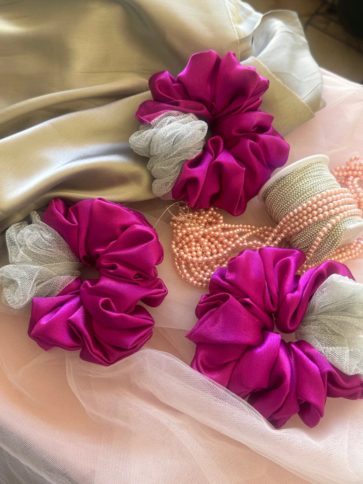 Three vibrant pink satin scrunchies with silver net detail from Bows and Bags India, handmade hair accessories displayed on