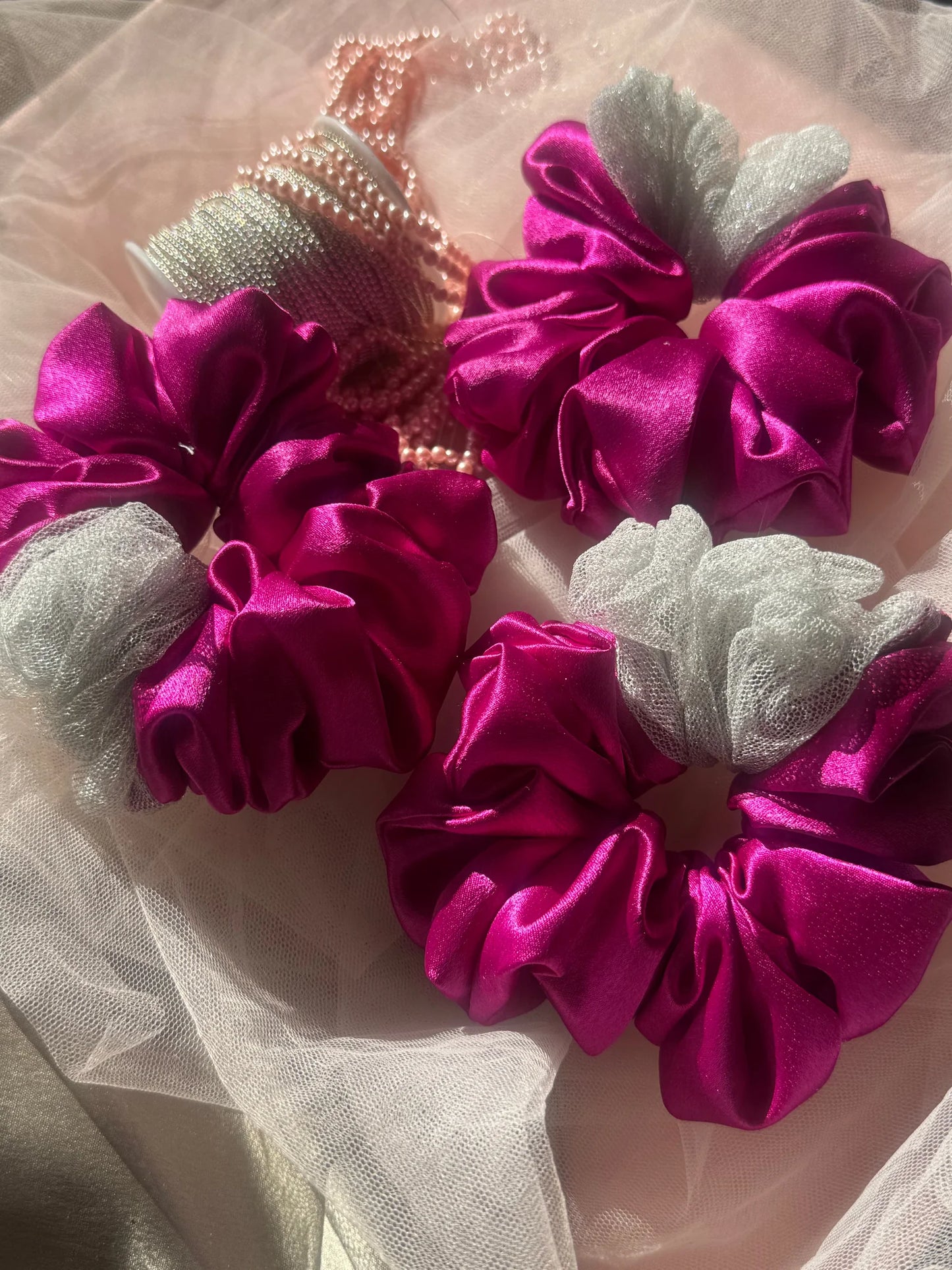 Vibrant pink satin scrunchies with silver net detailing by Bows and Bags India, handmade hair accessories displayed on sheer