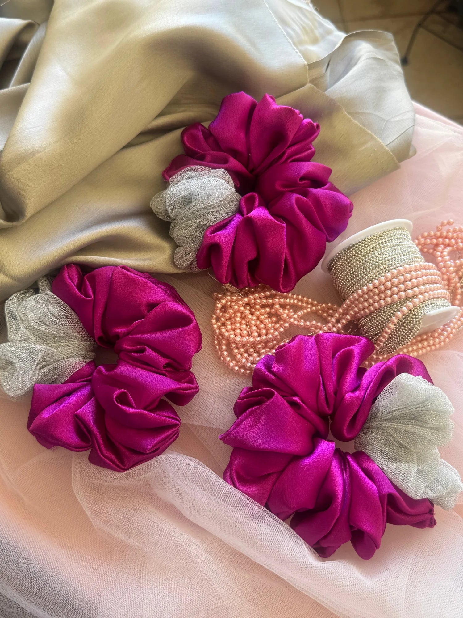 Pink and silver satin scrunchies with net detailing by Bows and Bags India, displayed on pink tulle fabric with pearl beads