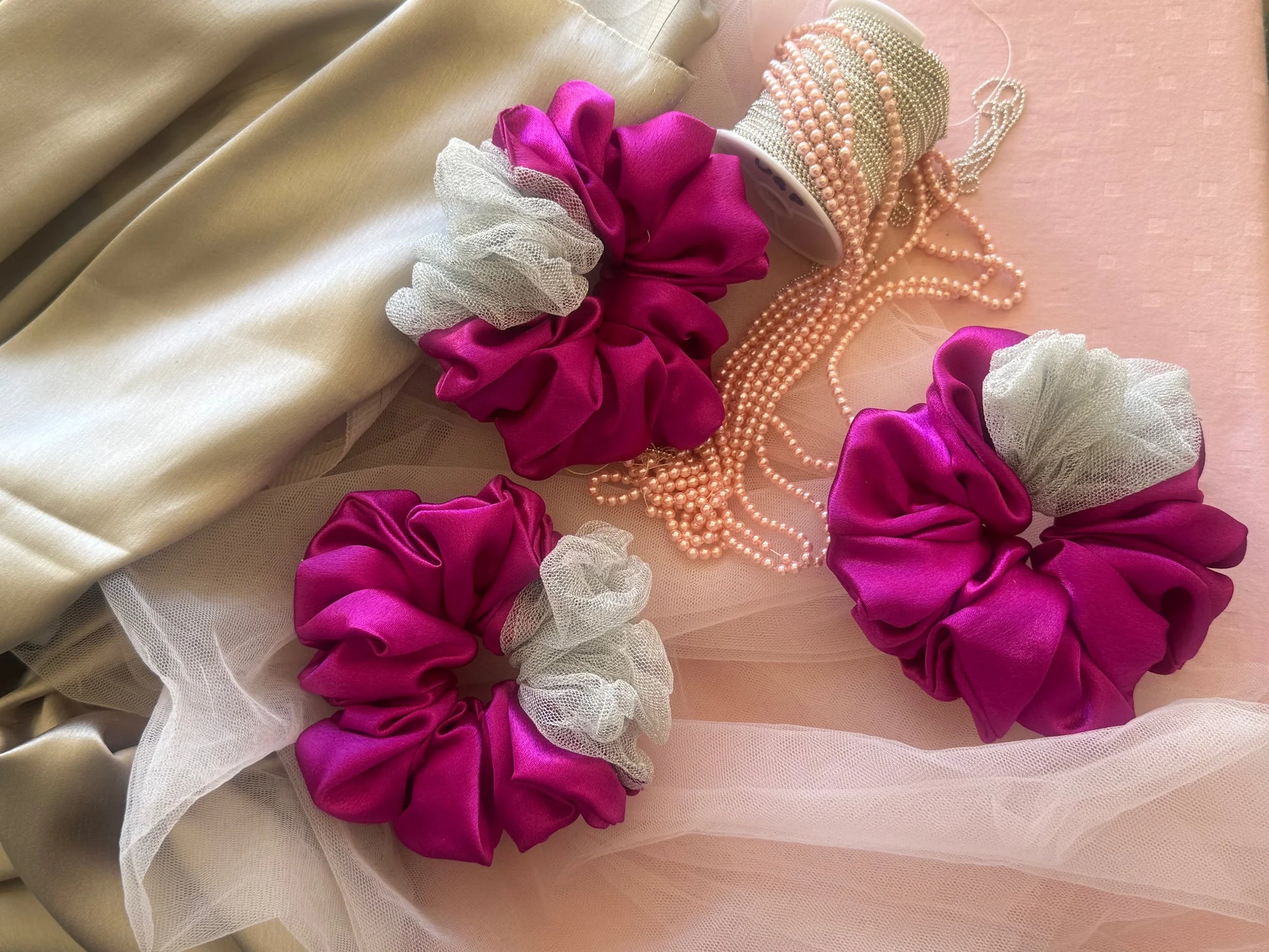 Pink silver satin scrunchies with net detail and pearl beads by Bows and Bags India handmade hair accessories styled flat lay