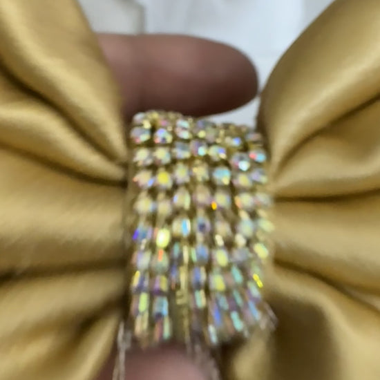 Close-up video of Goldy Bling Satin Hair Bow in gold, showcasing intricate stone and chain detailing, smooth satin texture, and secure French barrette clip