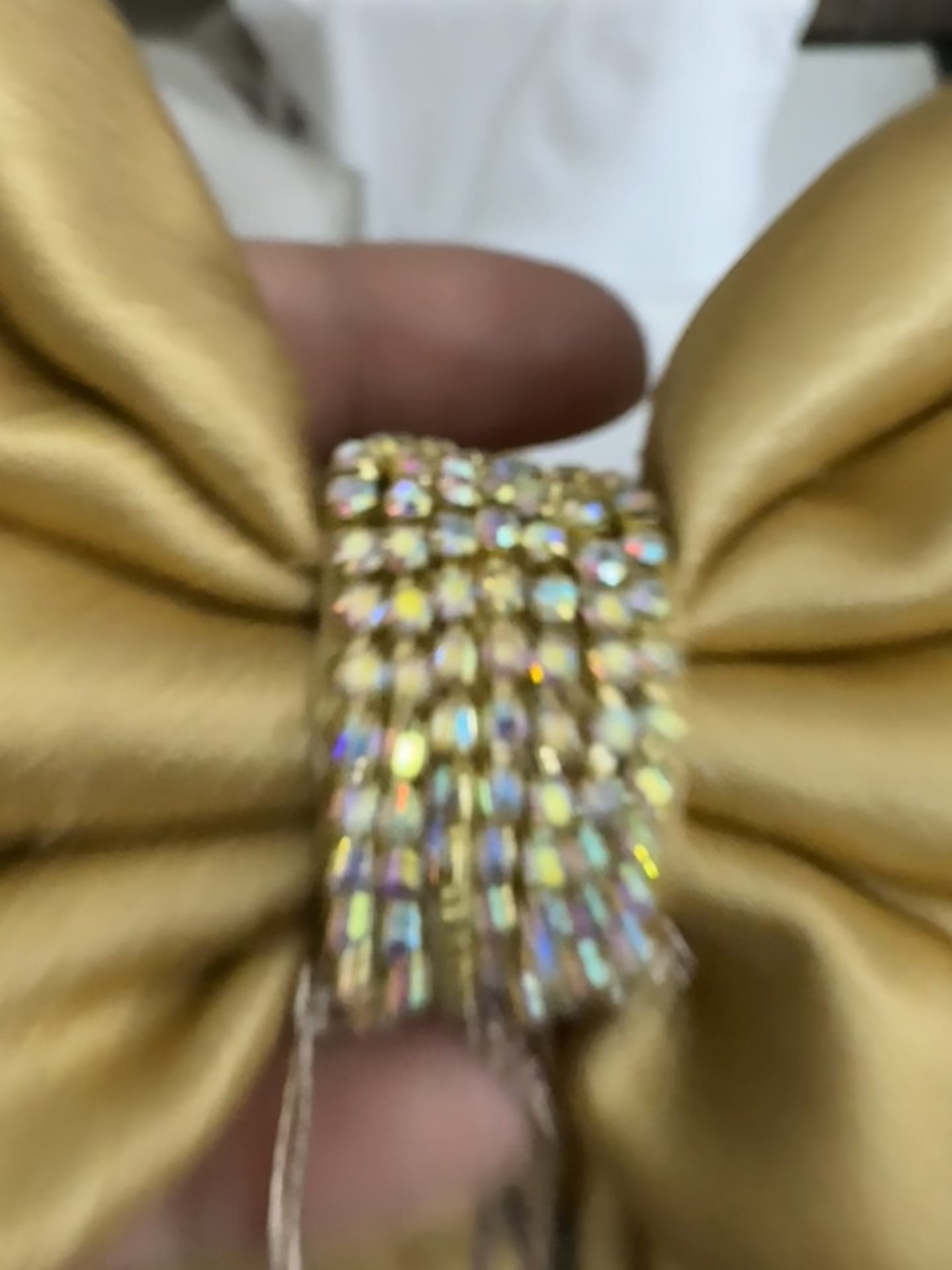 Close-up video of Goldy Bling Satin Hair Bow in gold, showcasing intricate stone and chain detailing, smooth satin texture, and secure French barrette clip