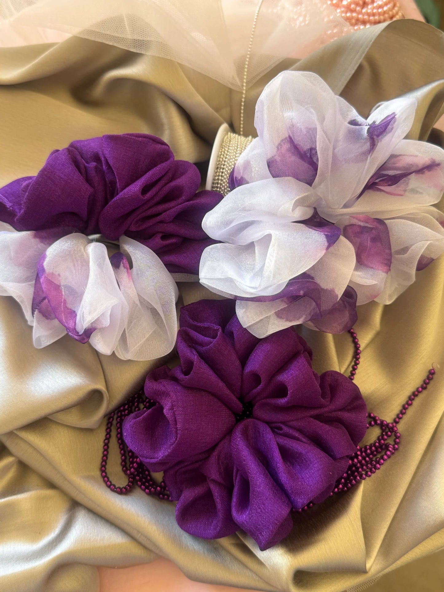 Purple silk and organza handmade scrunchies trio from Bows and Bags India displayed on gold fabric with floral details