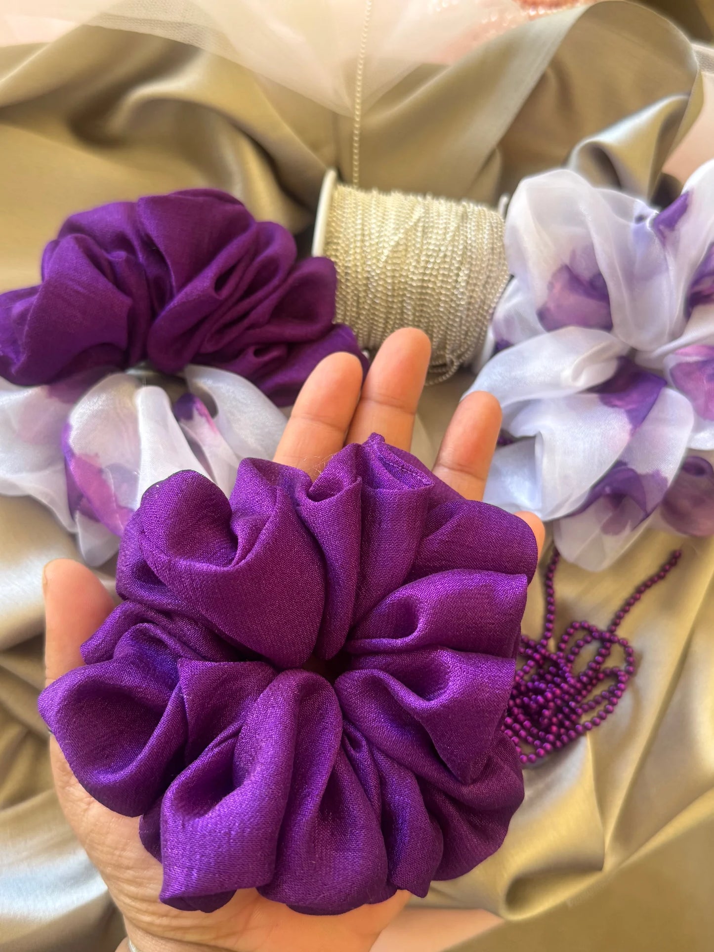 Purple silk scrunchie trio held in hand, showing luxe handmade texture and floral organza details by Bows and Bags India