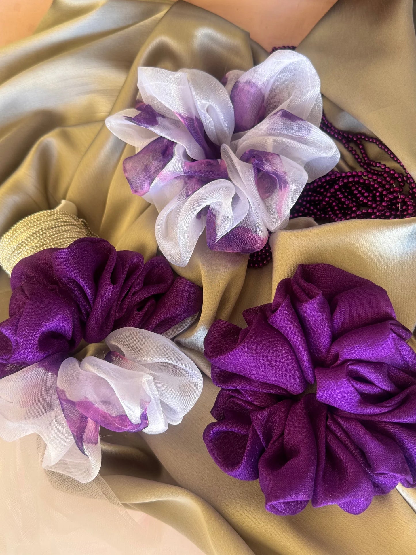 Purple silk and organza scrunchies trio from Bows and Bags India displayed on gold fabric, showing handmade hair accessories