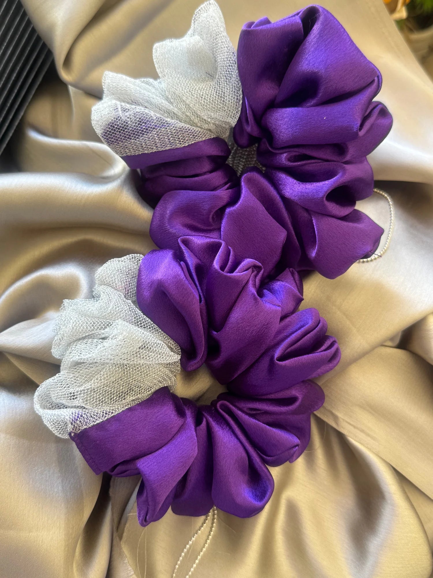 Purple and silver satin scrunchie with white net detail by Bows and Bags India, handmade hair accessory displayed on cream