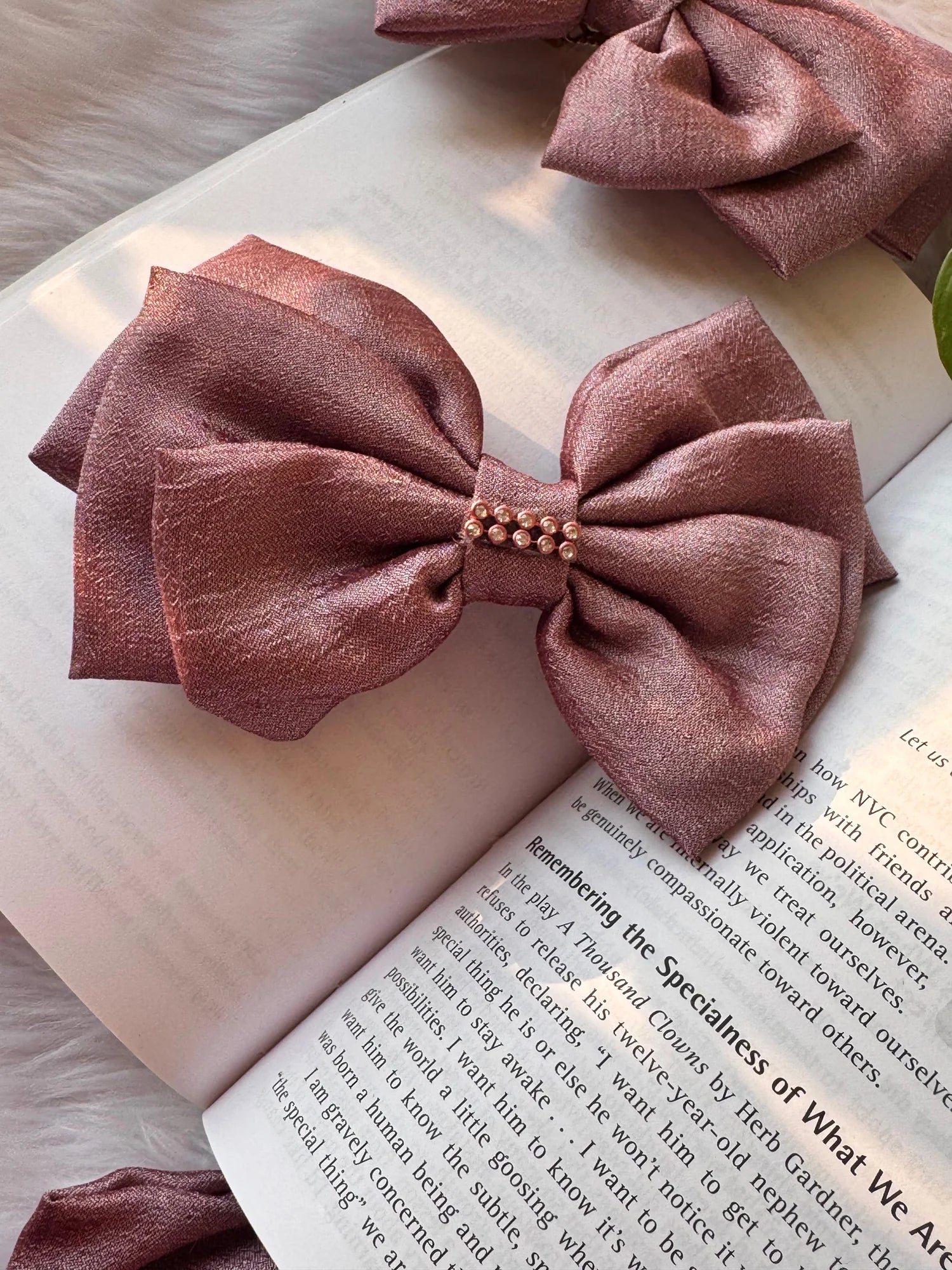 Rose gold silk hair bow with pearl stone embellishment on open book, Bows and Bags India handmade accessory detail shot